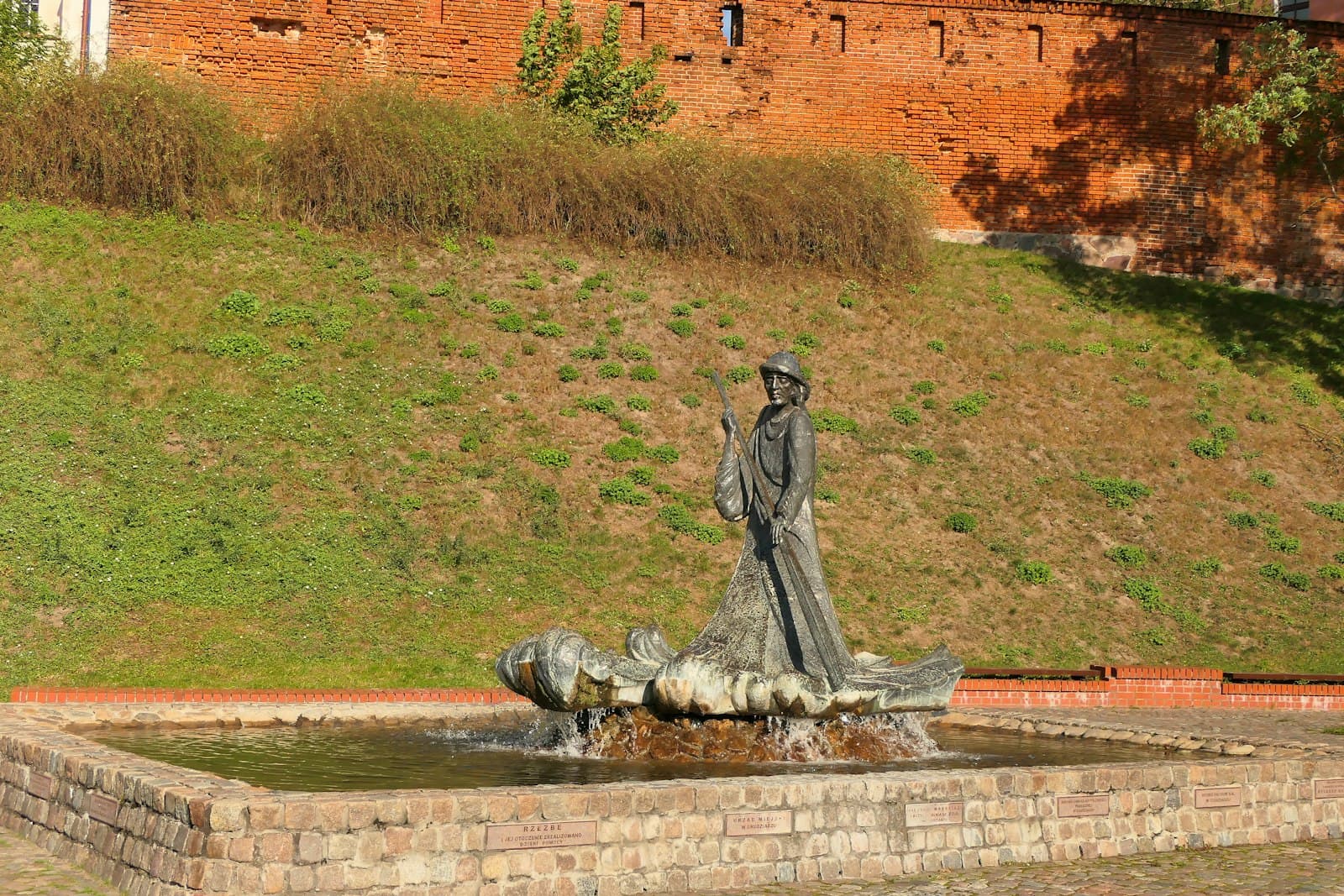 Grudziądz — a statue of a woman standing next to a fountain