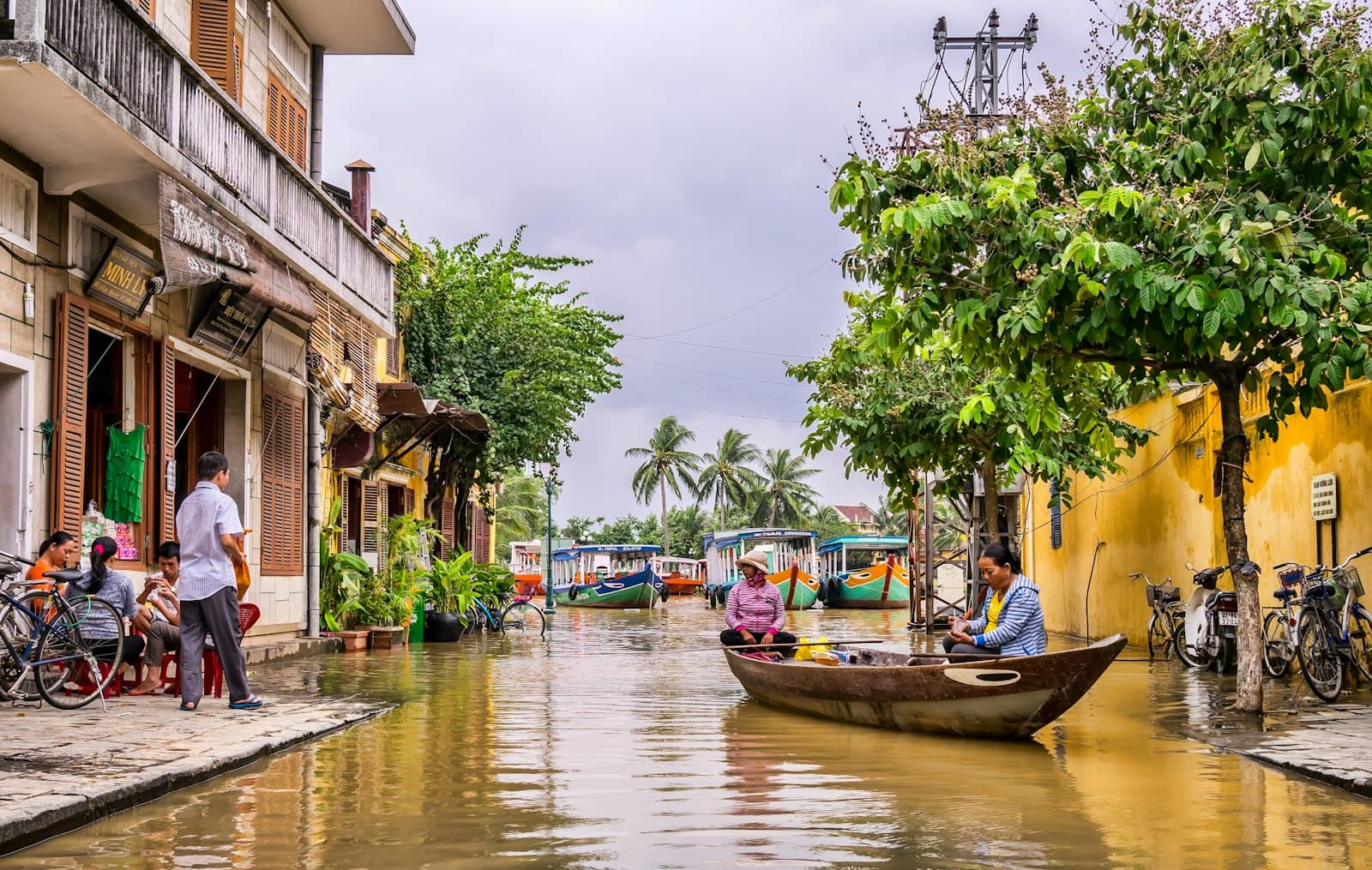 Hải Phòng — two women riding boat beside brown house