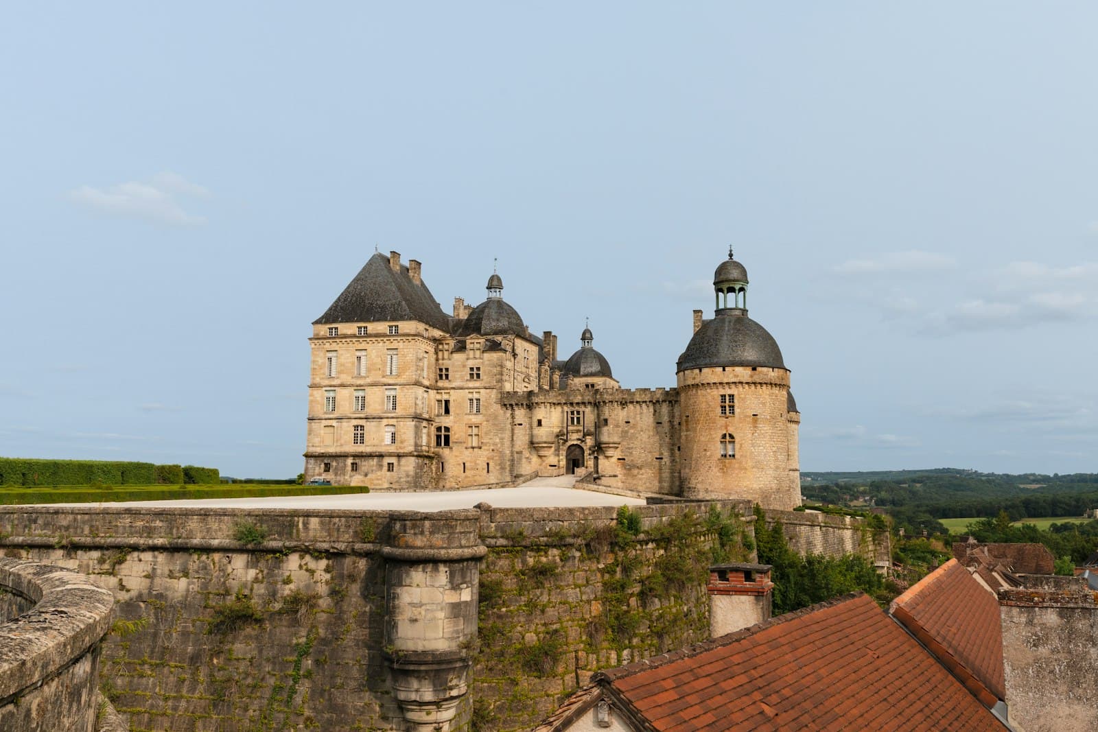 Hautefort — A large castle with a tower and a clock on top of it