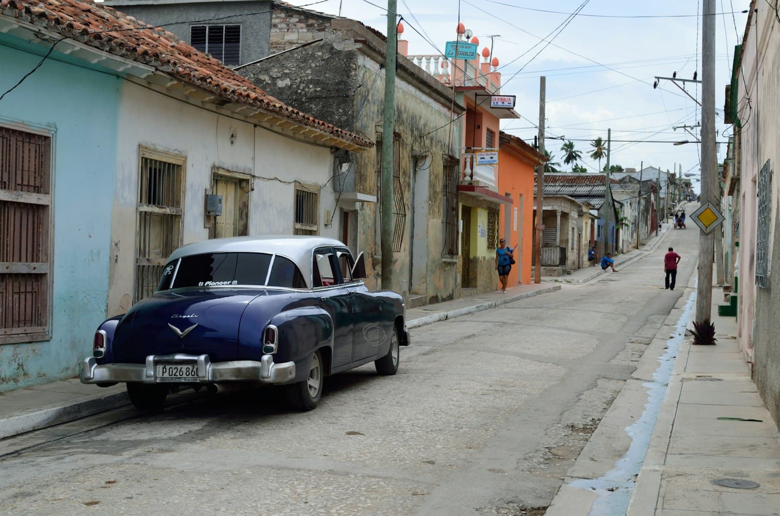 Holguín — blue car parked beside gray house