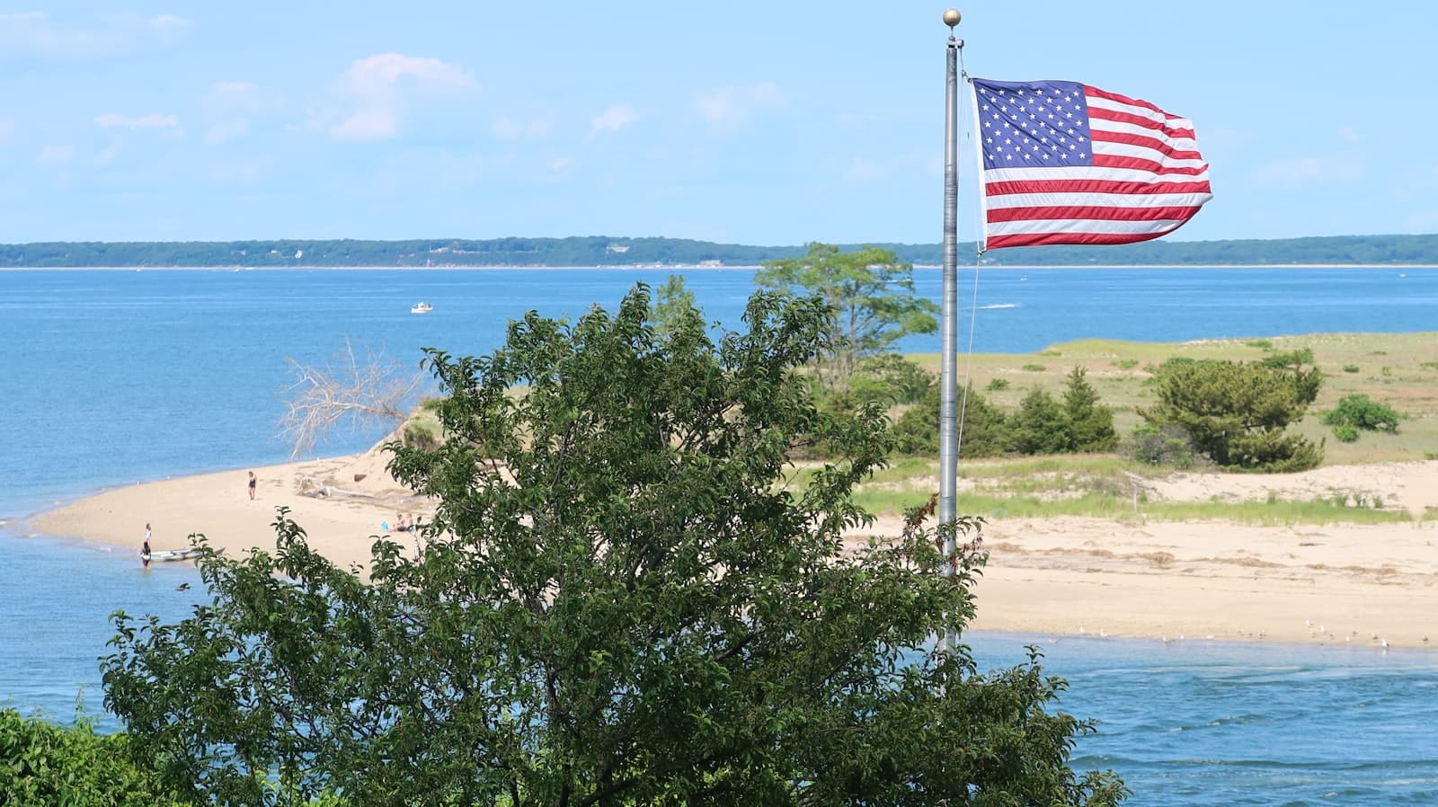Hyannis — a large american flag flying over a beach next to a body of water