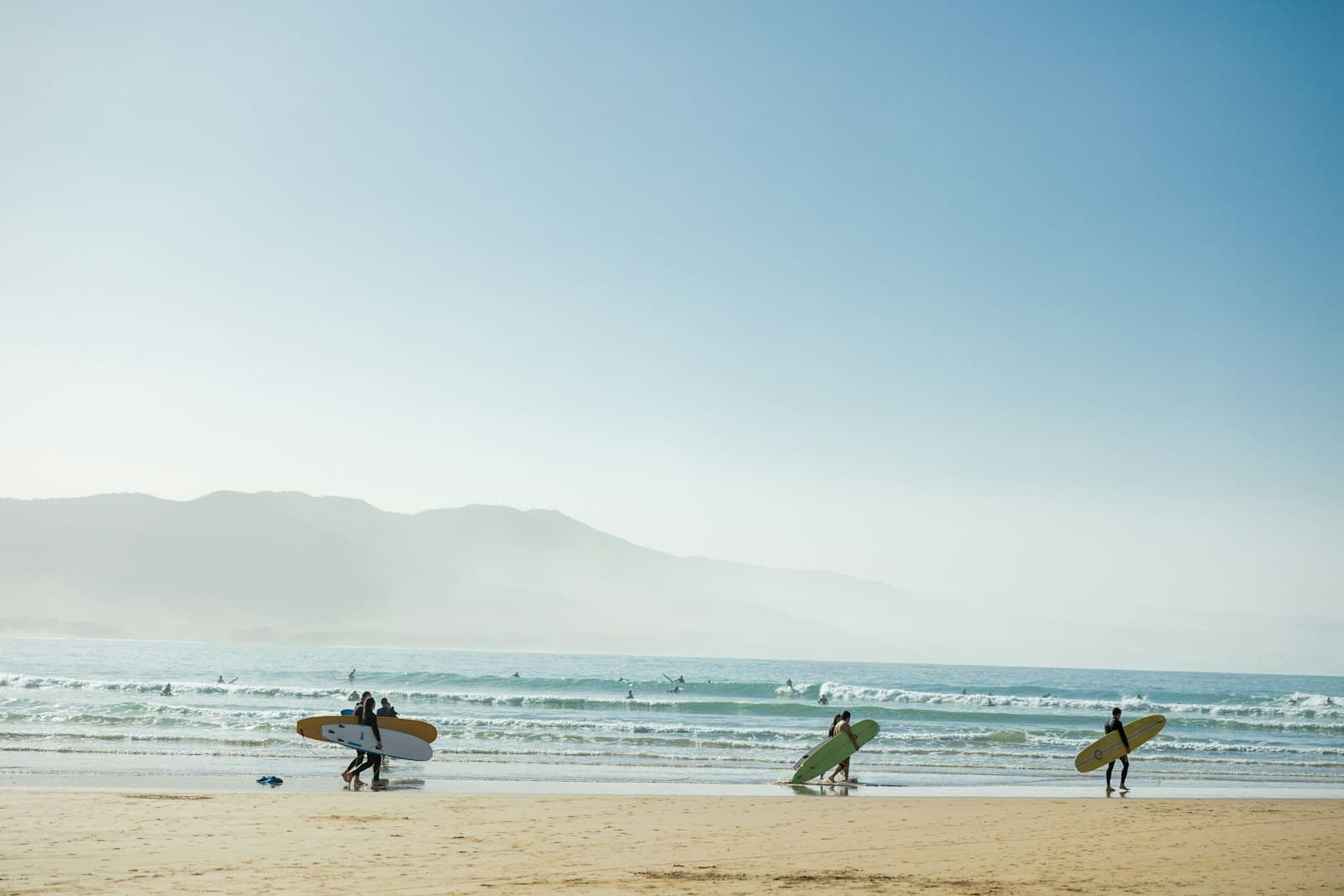 Imsouane — a group of people carrying surfboards on top of a beach