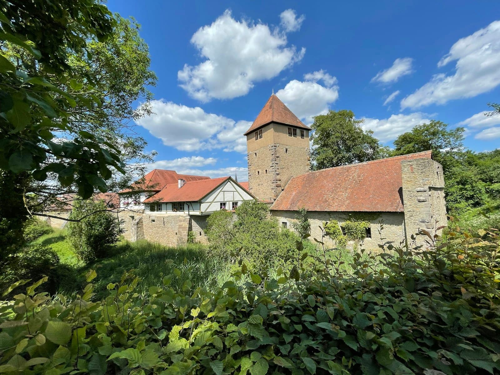 Iphofen — a building with a tower surrounded by trees and bushes