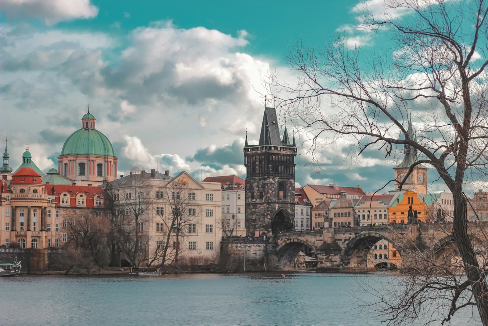 Kafka's Prague — brown and green concrete building beside body of water under blue sky during daytime