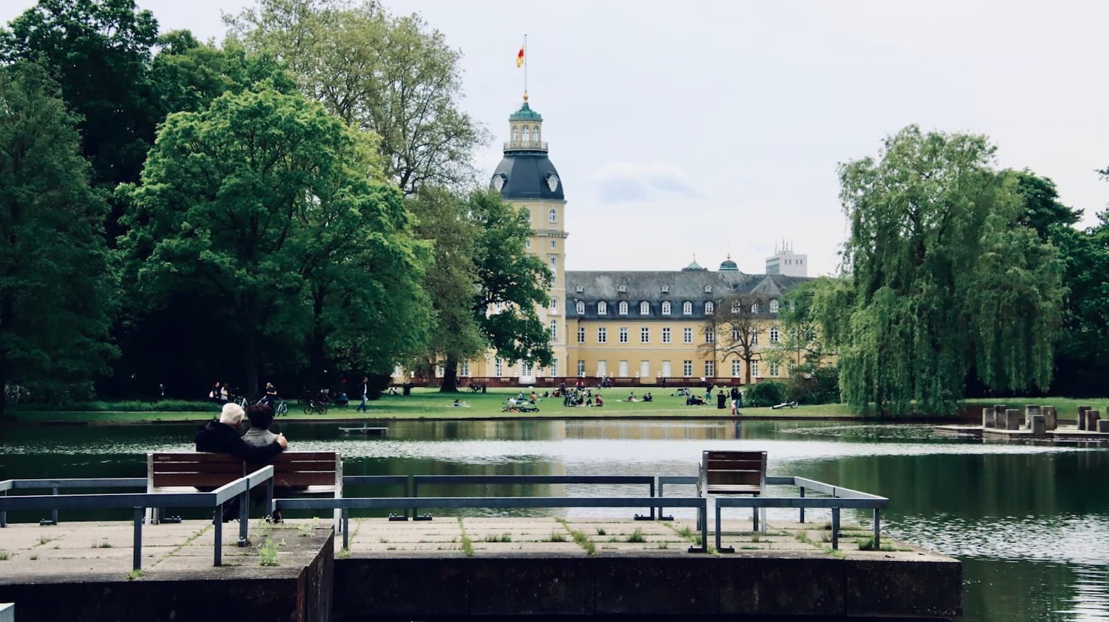 Karlsruhe — people sitting on bench near body of water during daytime