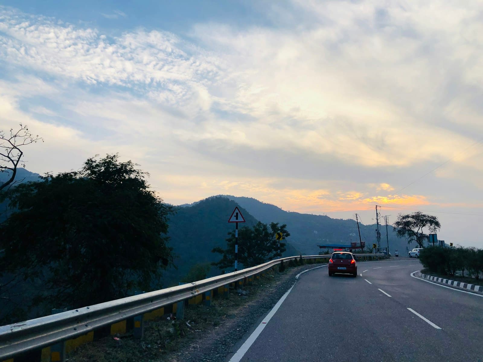 Kasauli — a car driving down a road with mountains in the background