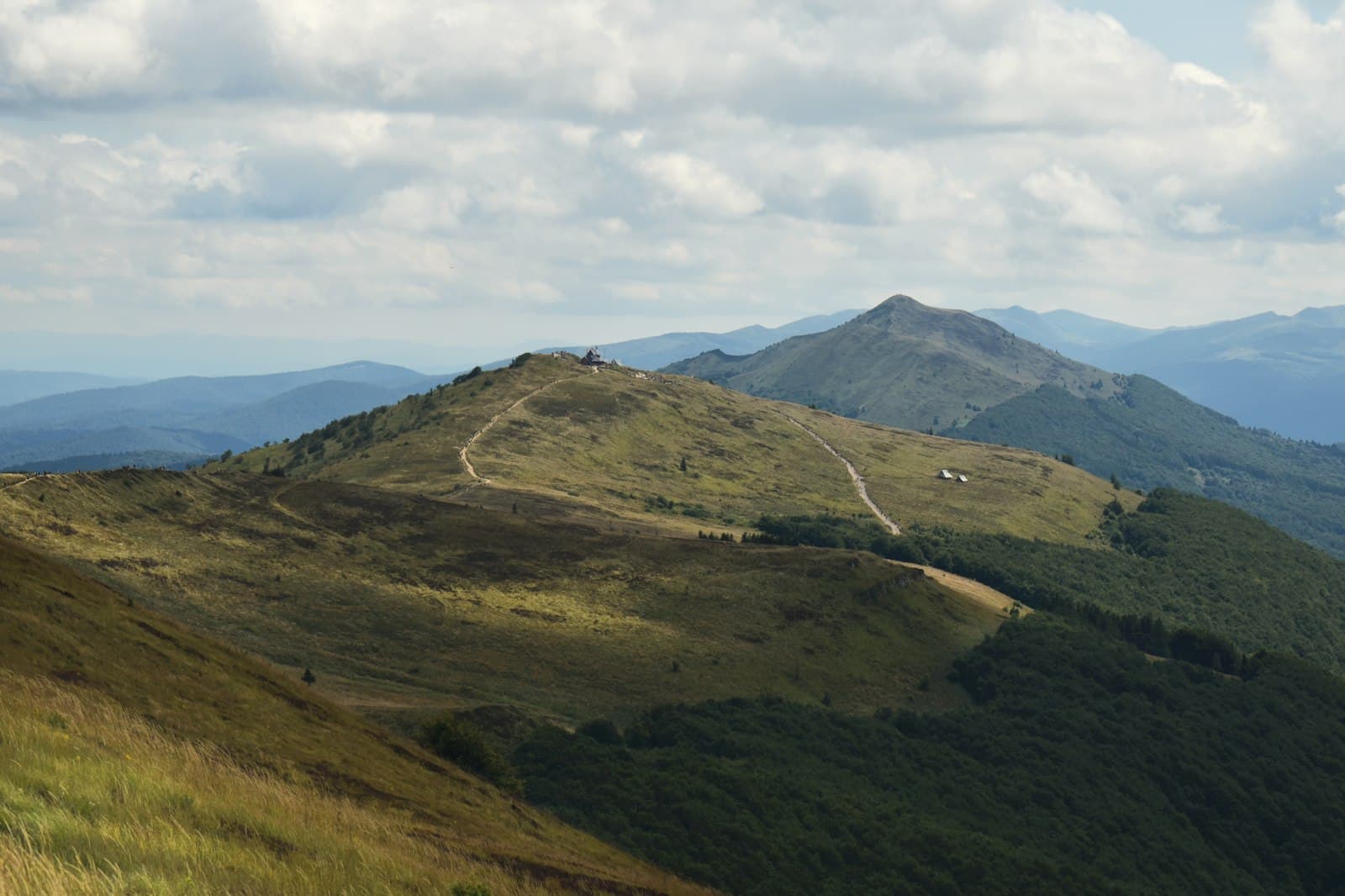 Kazimierz Bieszczady — Rolling green hills with a path under a cloudy sky