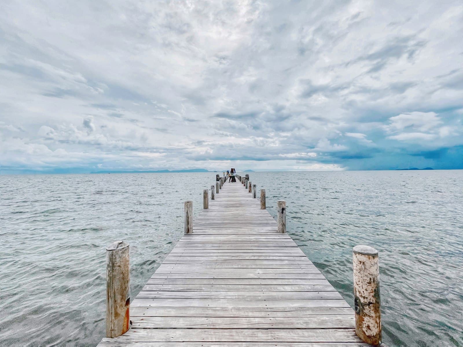 Kep — a wooden pier extending into the ocean under a cloudy sky