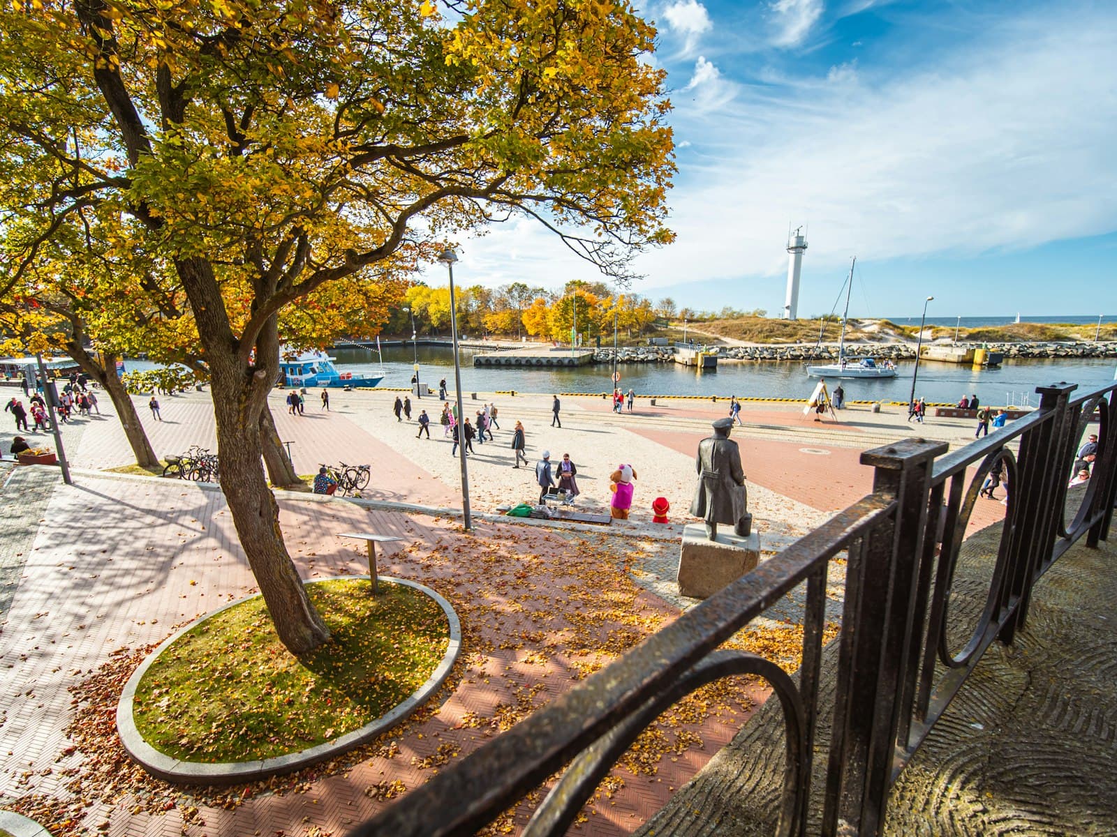 Kołobrzeg — a group of people walking around a park next to a river