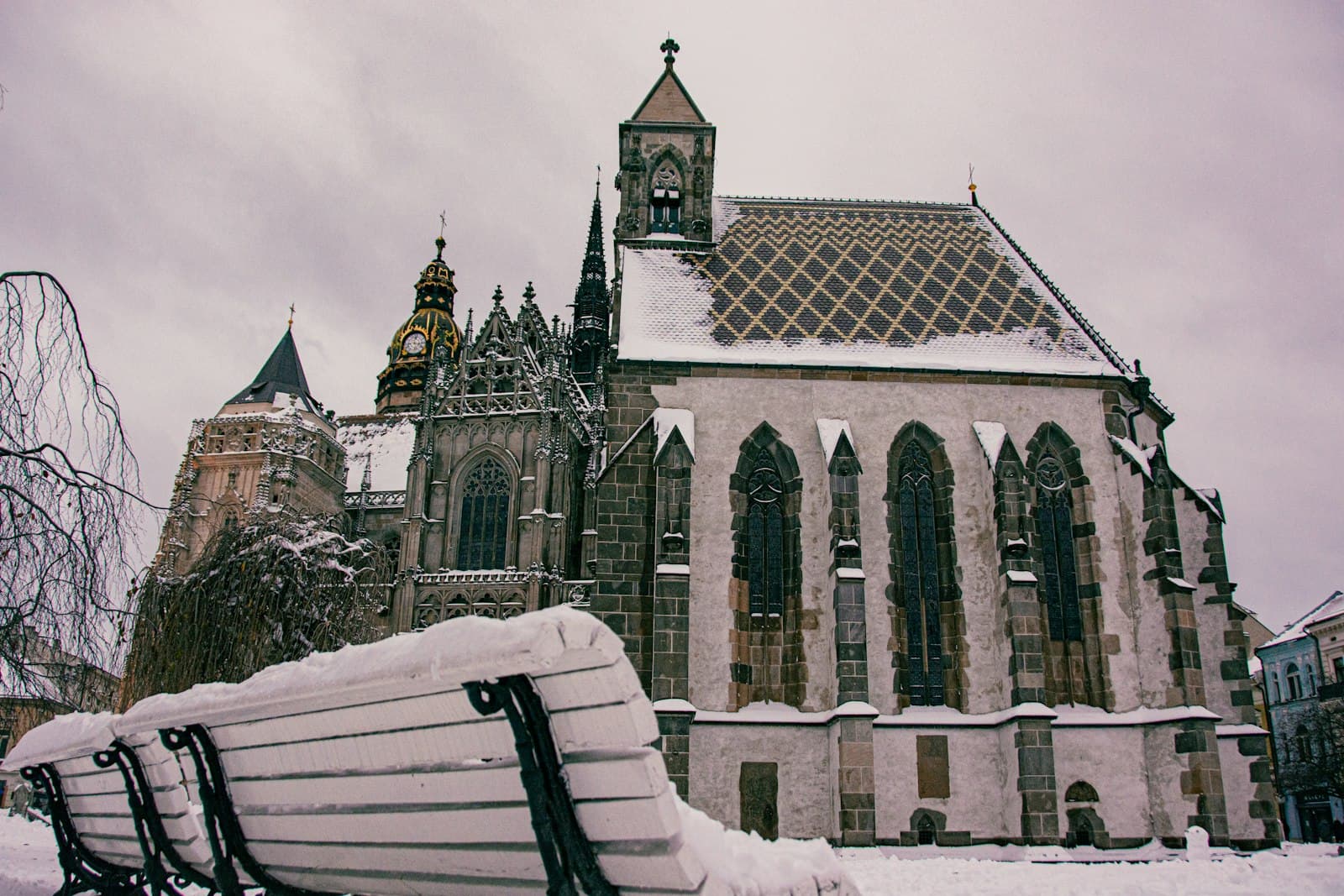 Košice — a bench covered in snow in front of a church