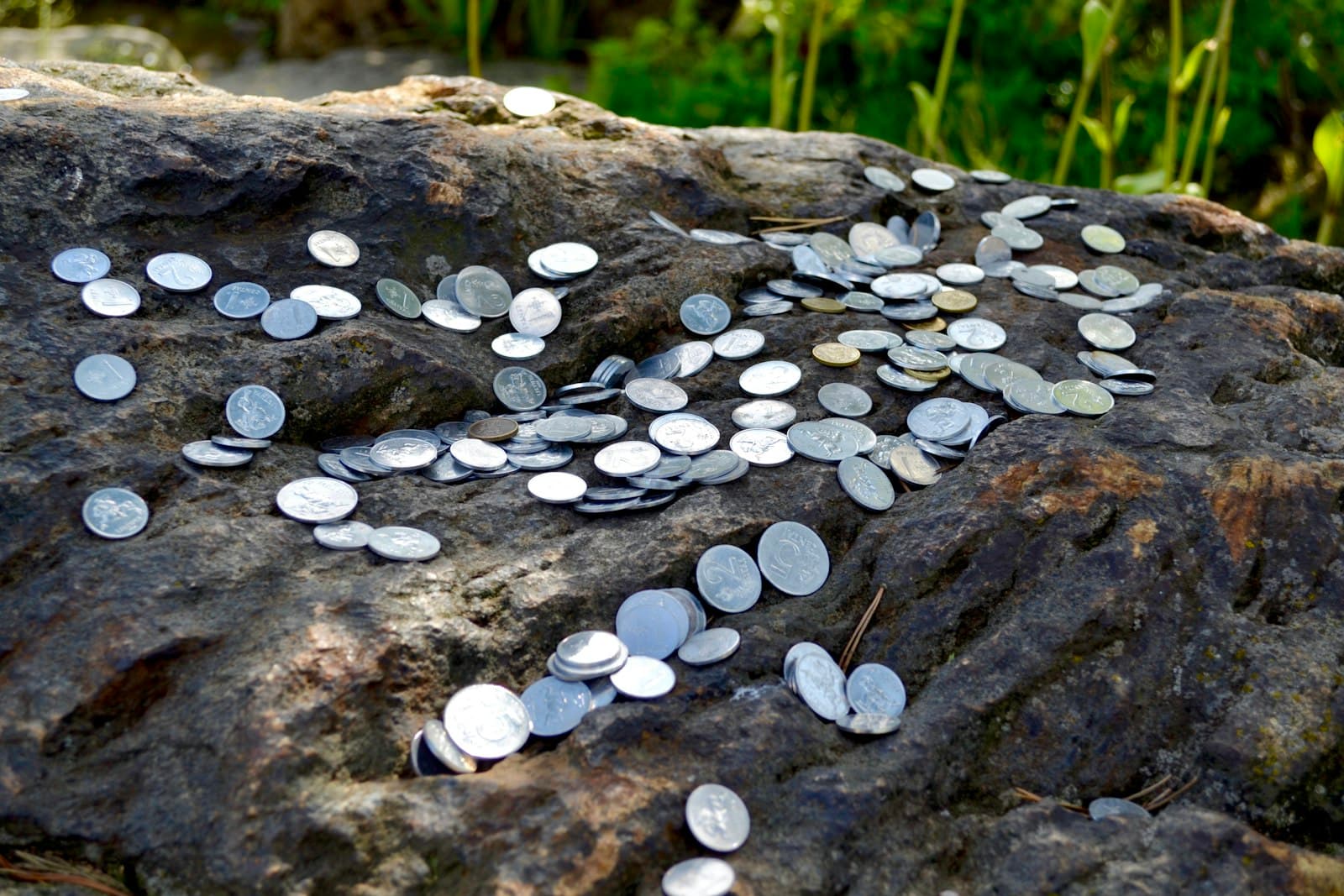 Kretinga — Coins scattered on a rough, dark rock surface