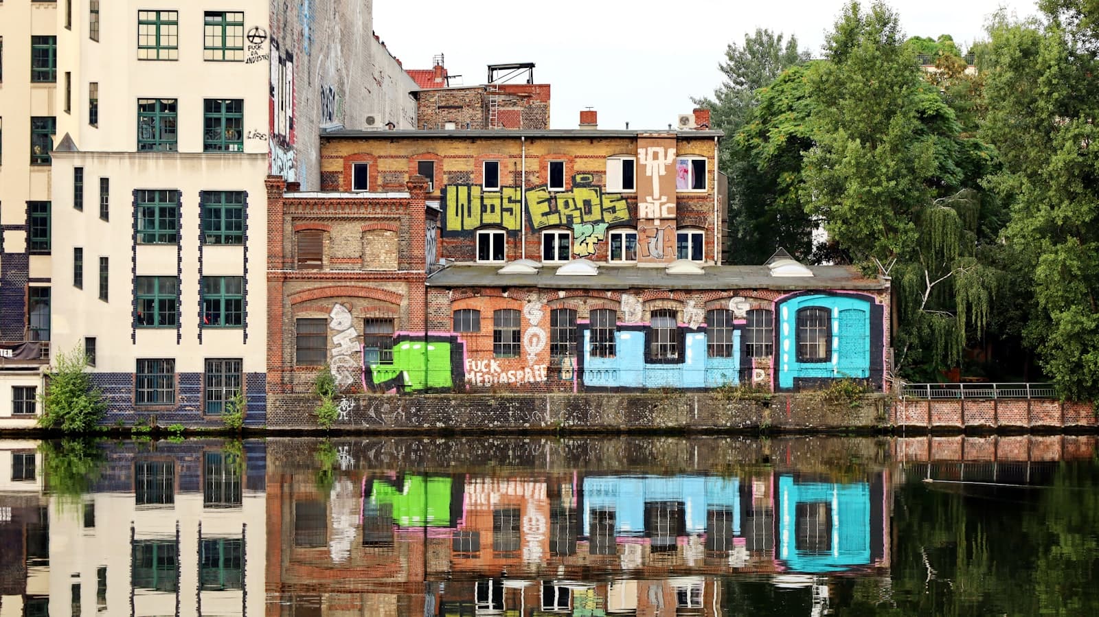 Kreuzberg Street Art — a building with graffiti on the side of it next to a body of water
