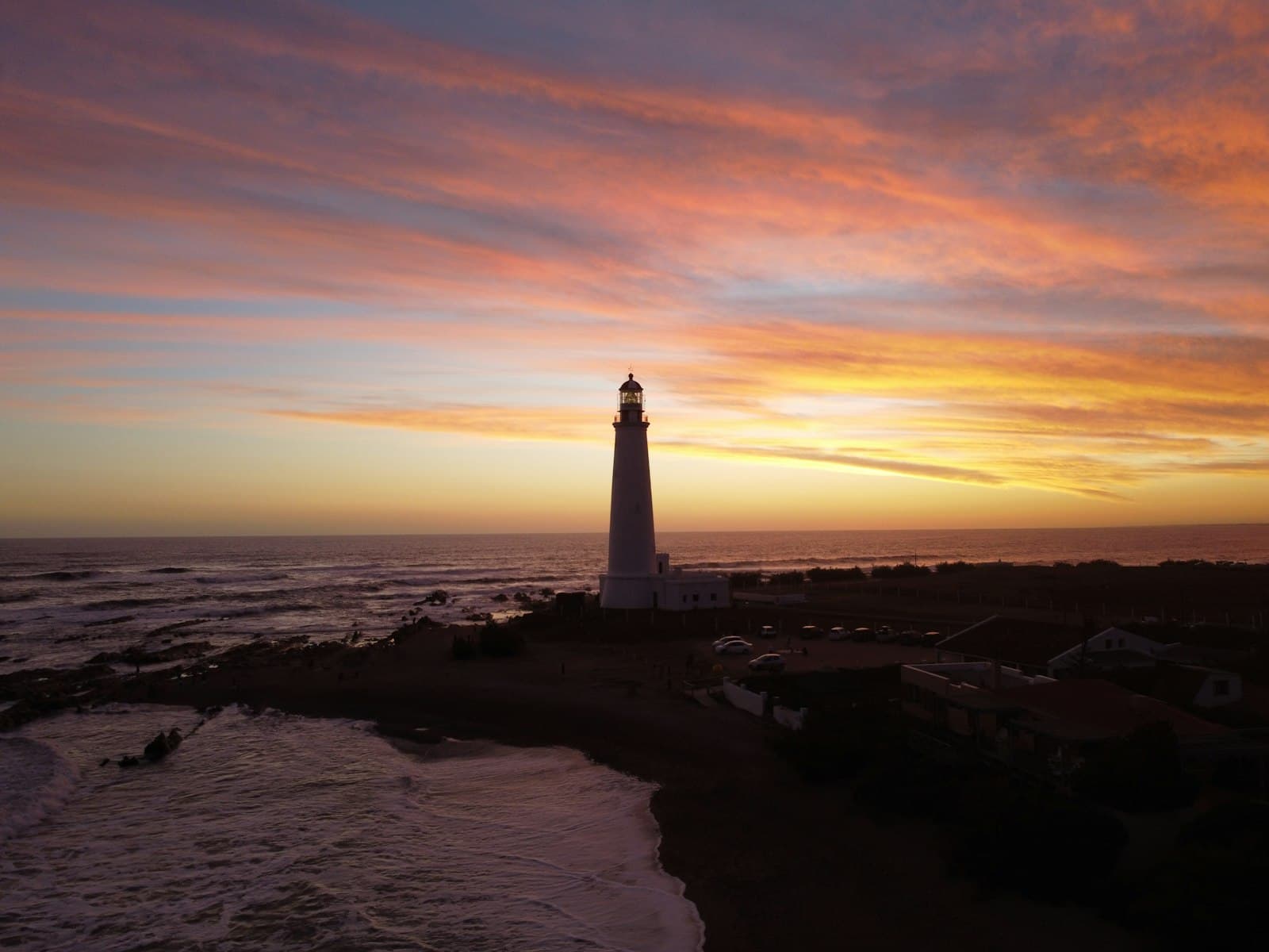 La Paloma — white and black lighthouse on brown sand during sunset