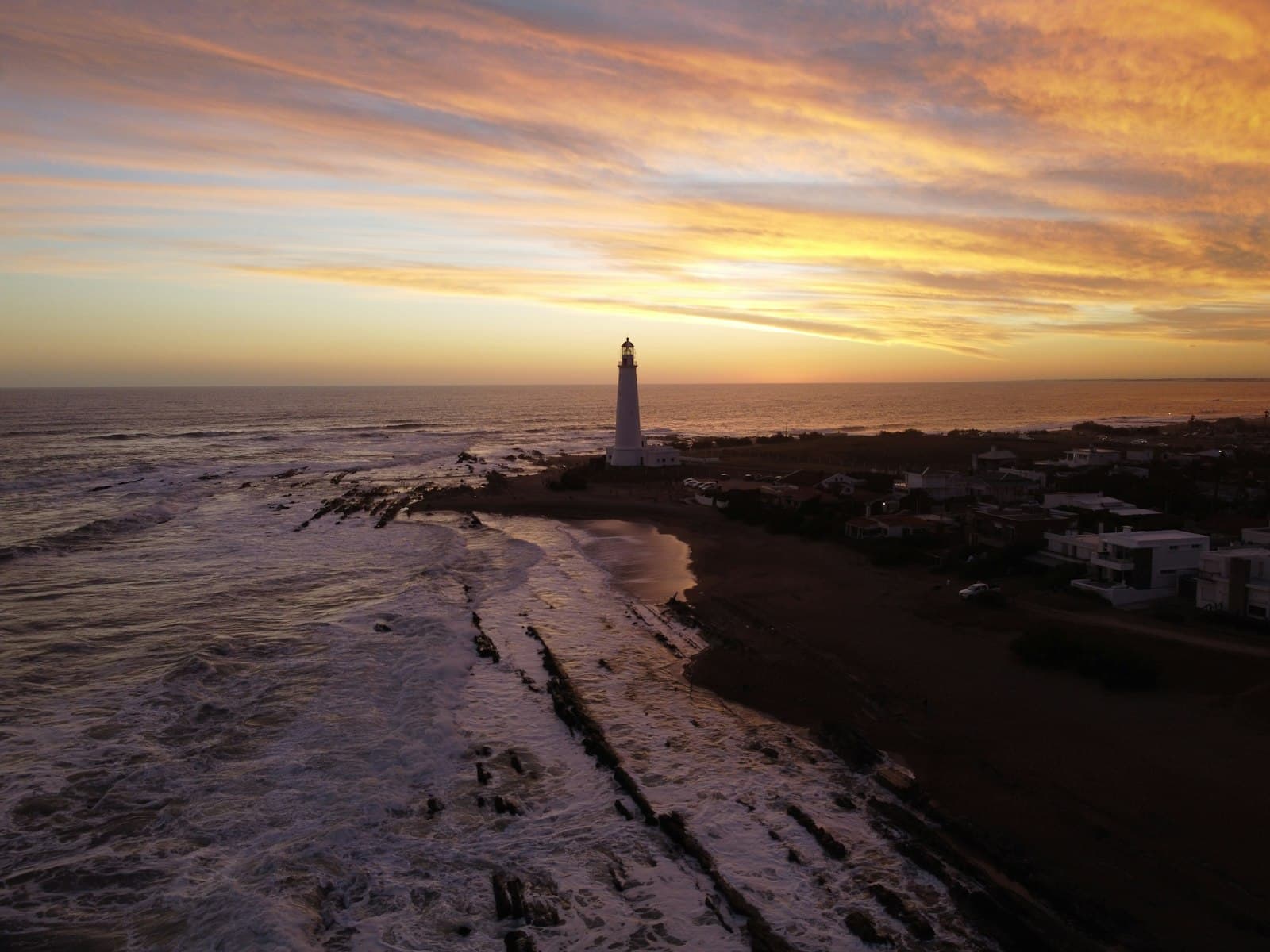 La Paloma — white lighthouse on gray sand during sunset