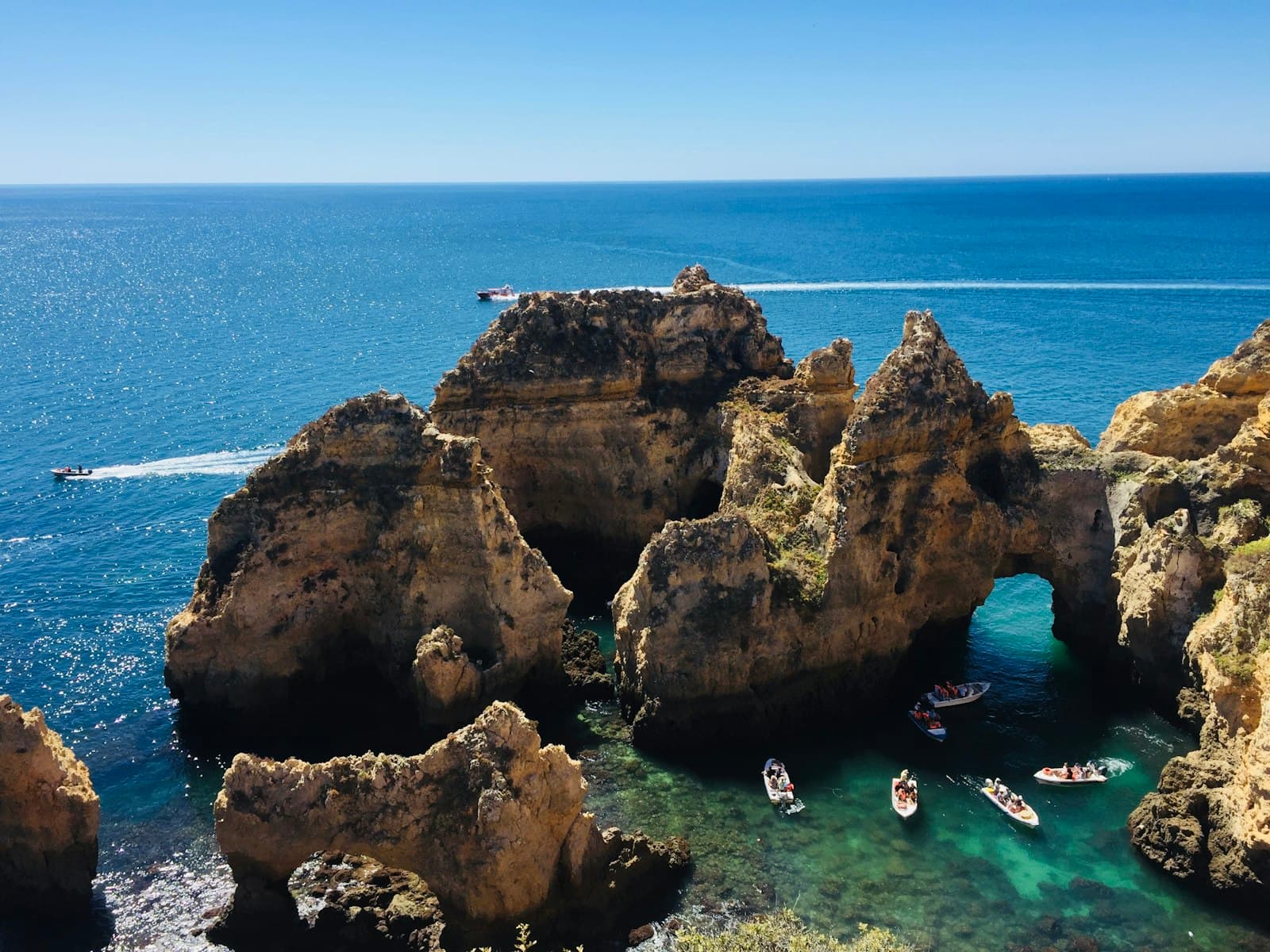 Lagos — people swimming on sea near brown rock formation during daytime