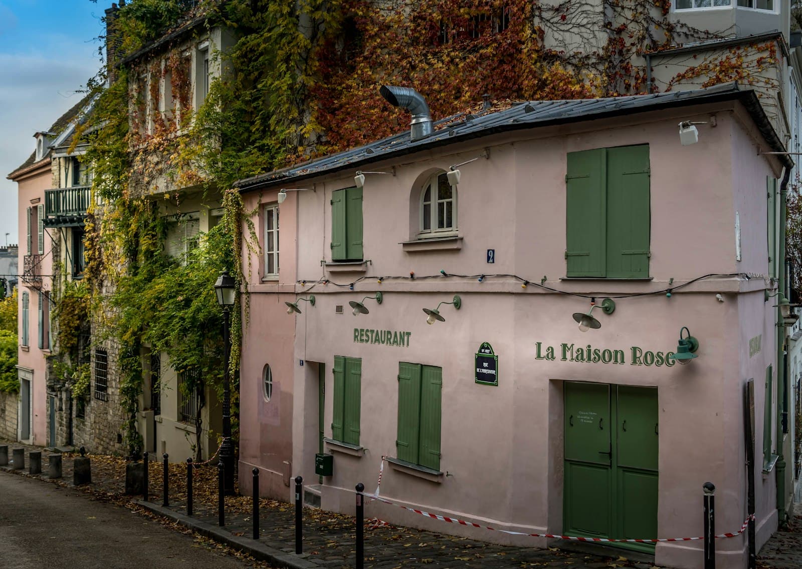 Le Faou — a pink building with green shutters next to a street