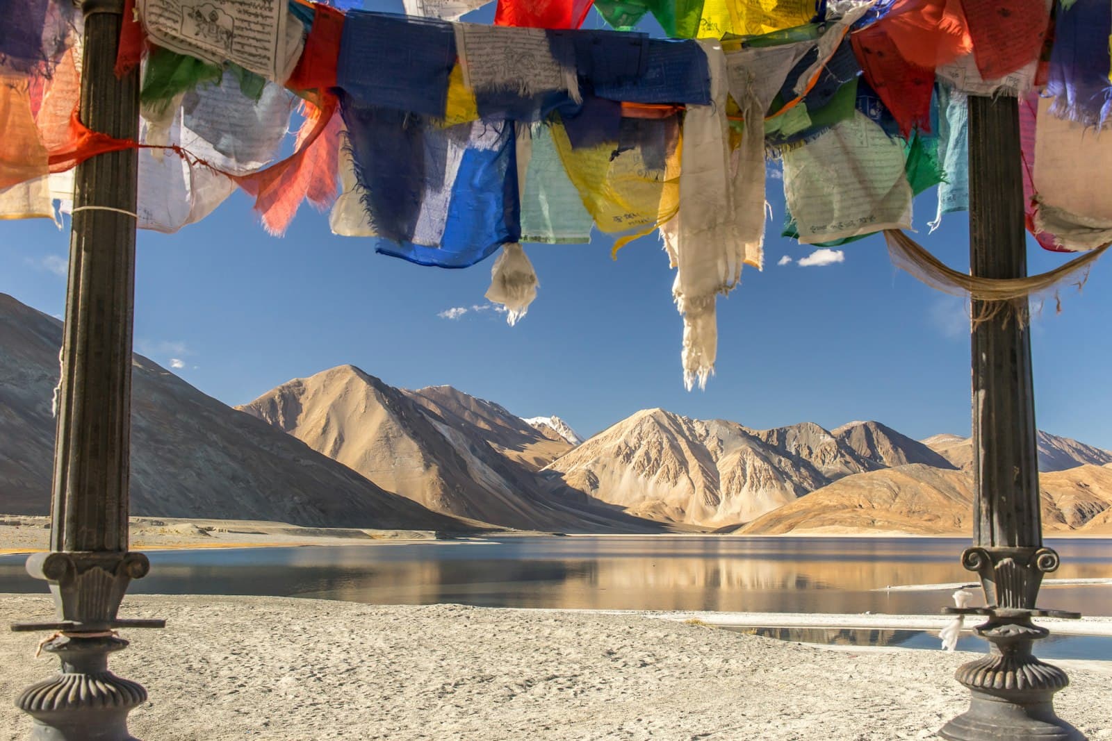 Leh — blue yellow and red textile on gray sand near lake and mountain during daytime
