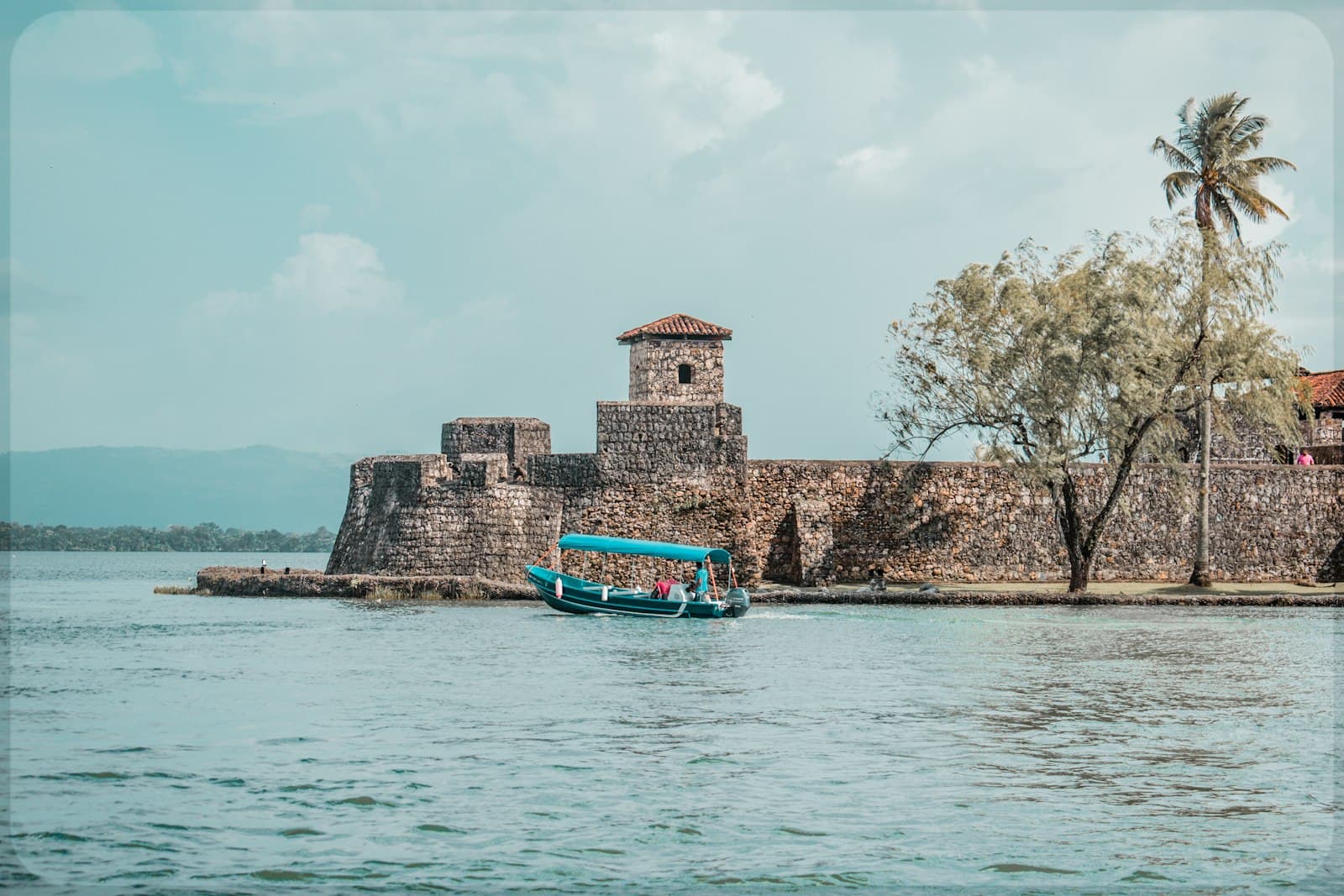 Livingston — a blue boat traveling down a river next to a stone wall