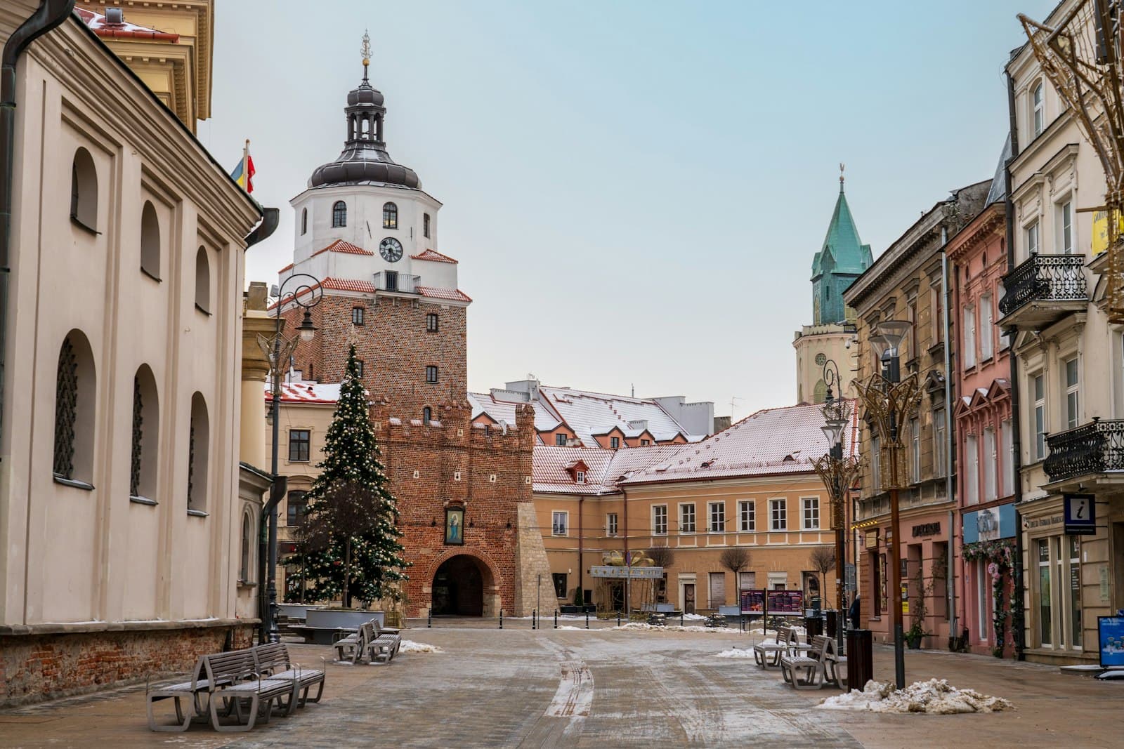 Lublin — a snowy street with benches and a church in the background