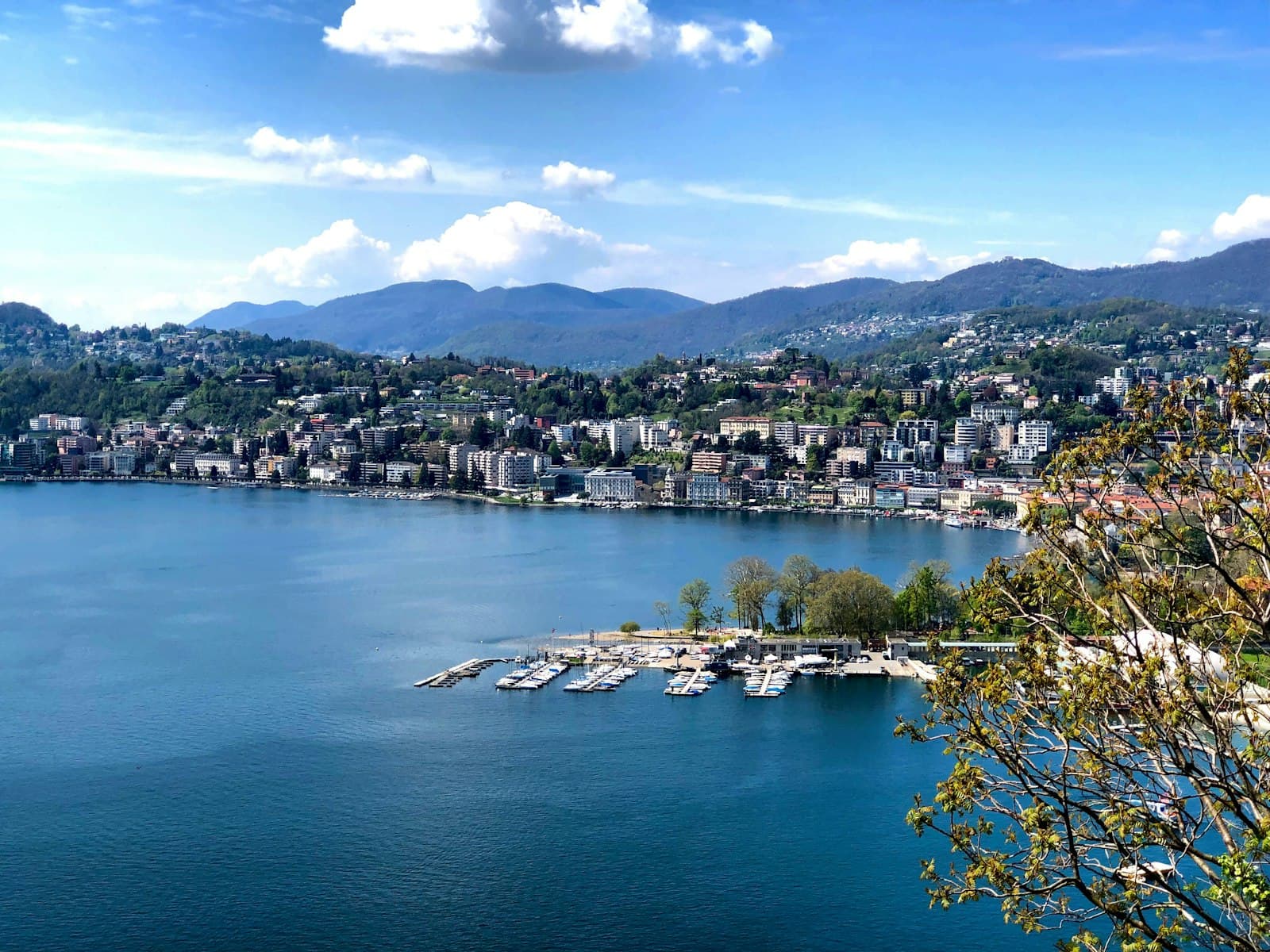 Lugano — aerial view of city buildings near body of water during daytime