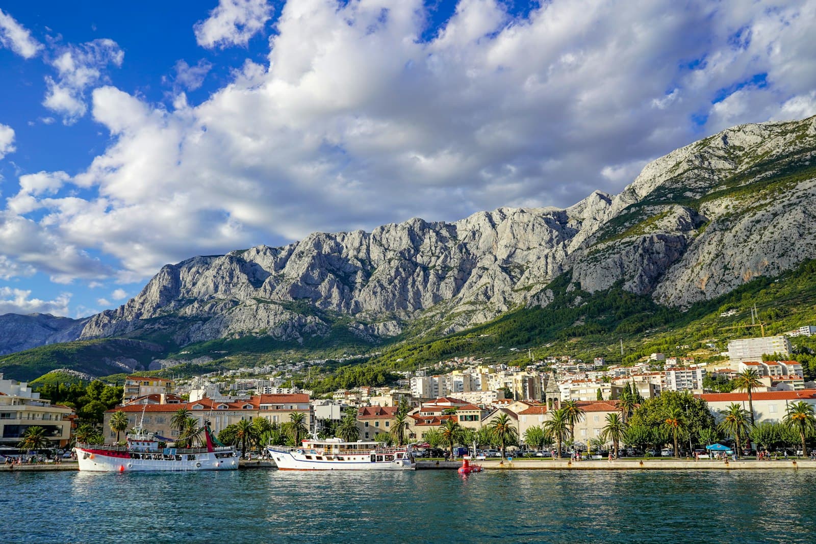 Makarska — white and brown concrete building near body of water under white clouds and blue sky during