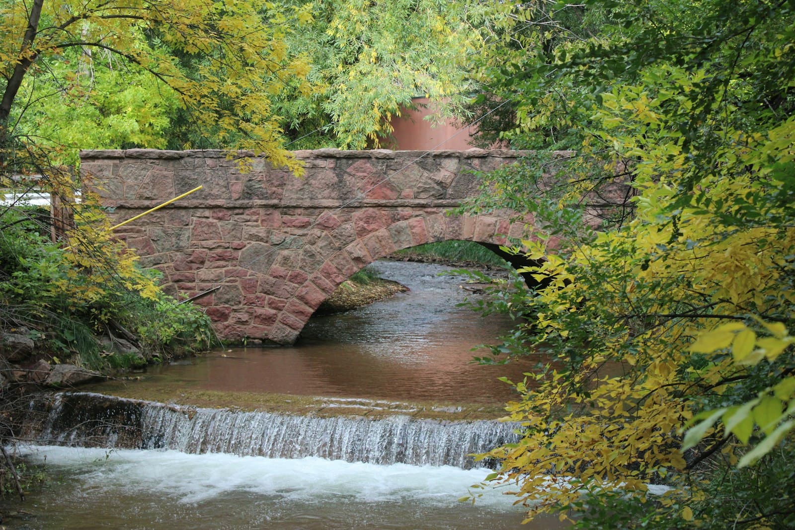 Manitou Springs — Stone bridge over a stream with autumn foliage