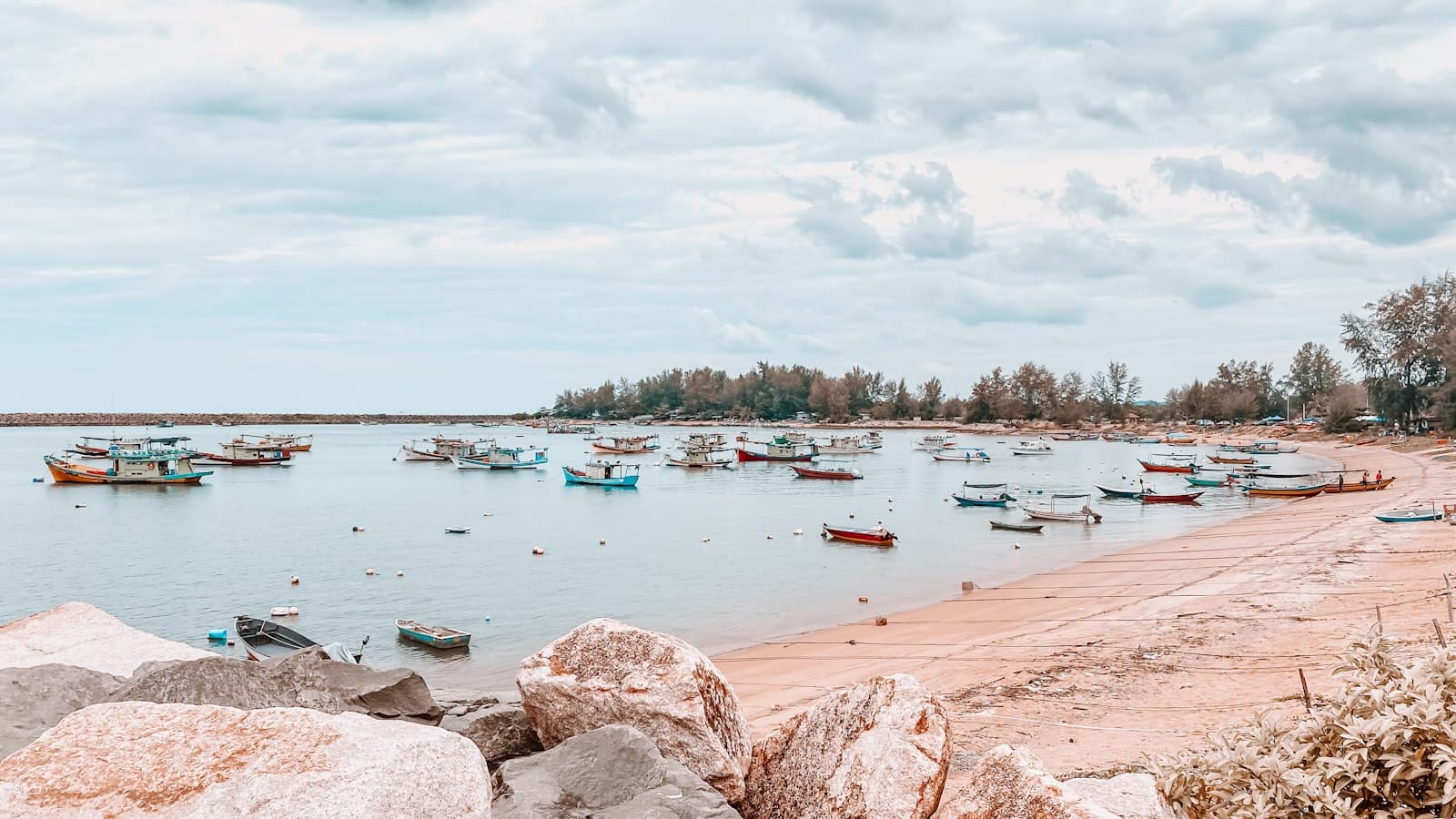 Marang — boats on sea near rocks under cloudy sky during daytime