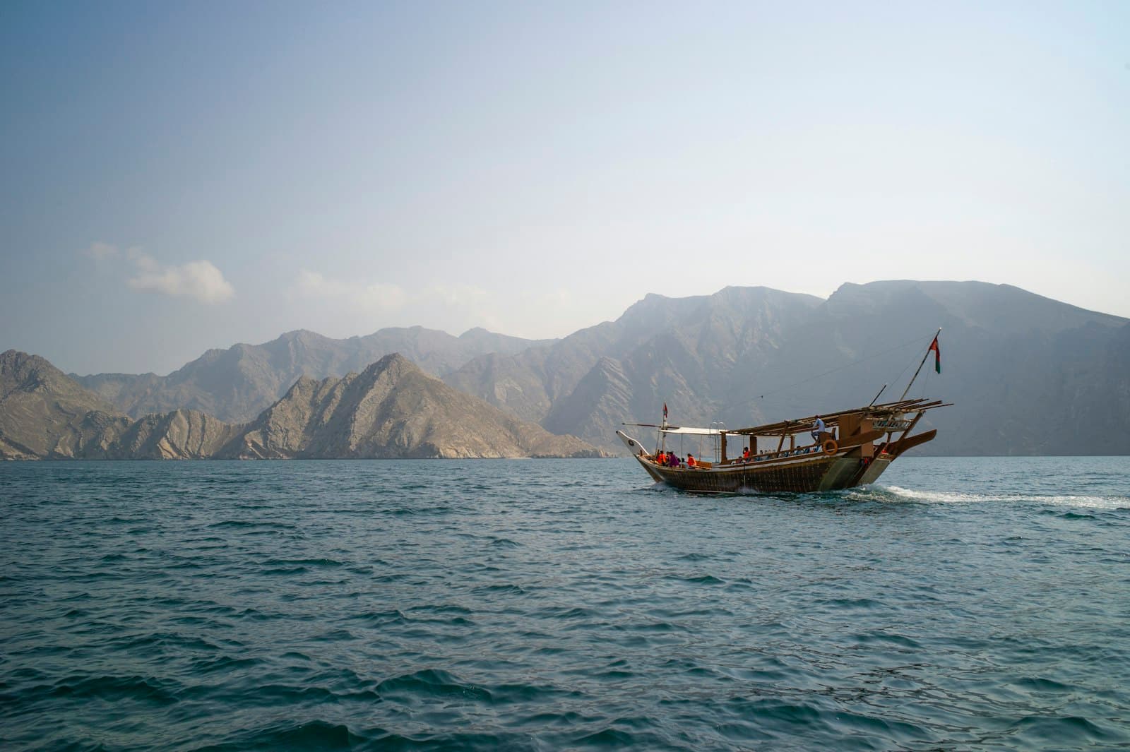 Mascate — brown boat on sea near mountain during daytime