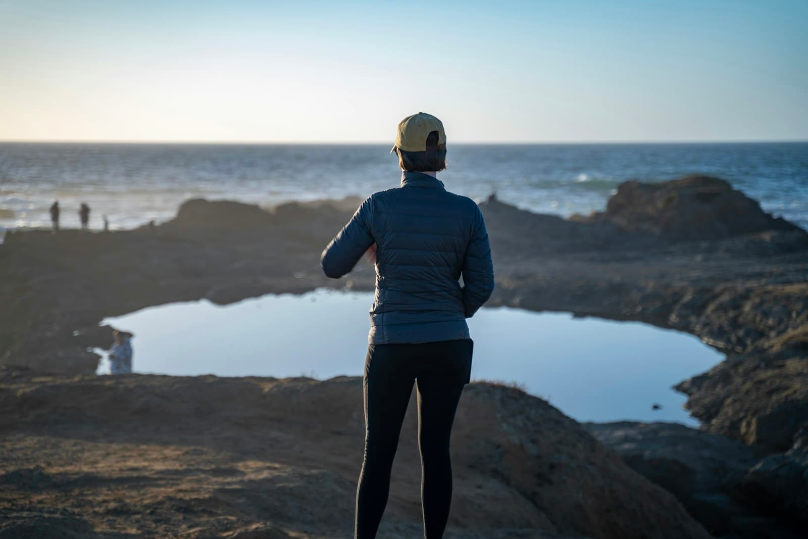 Mendocino — a woman standing on top of a rocky beach next to the ocean