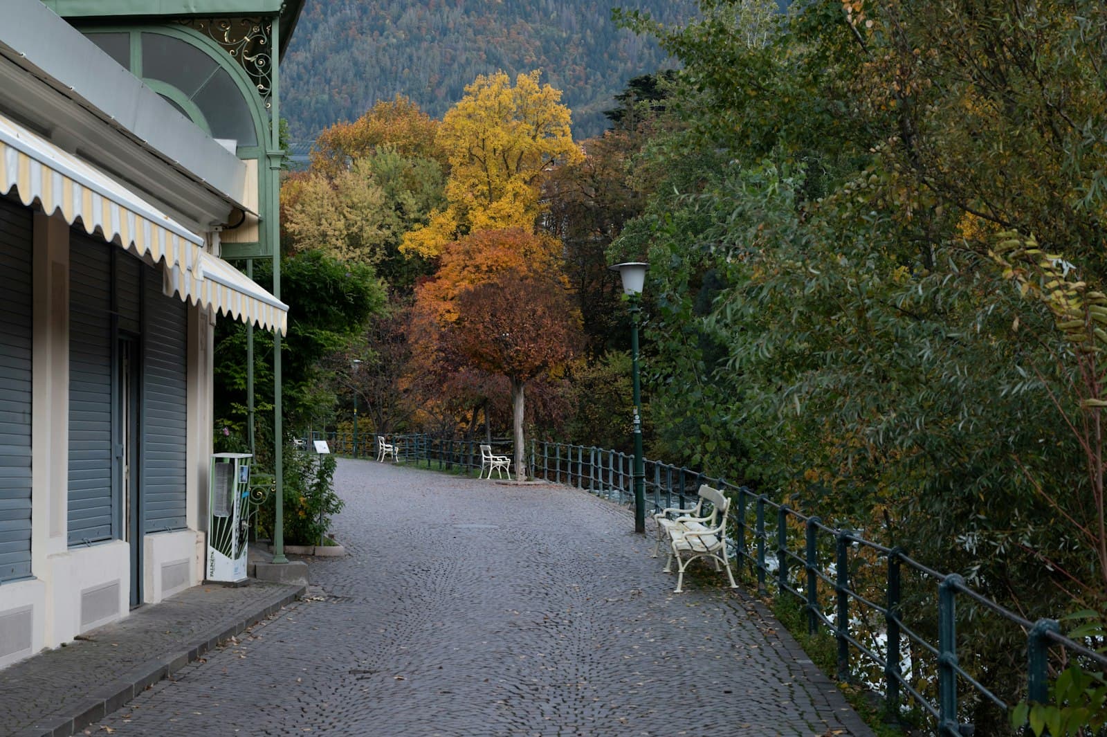 Merano — a cobblestone street with a row of tables and chairs