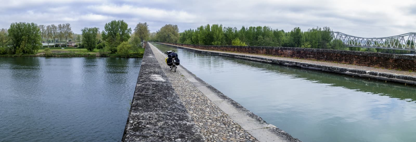 Moissac — a man riding a motorcycle down a river next to a bridge