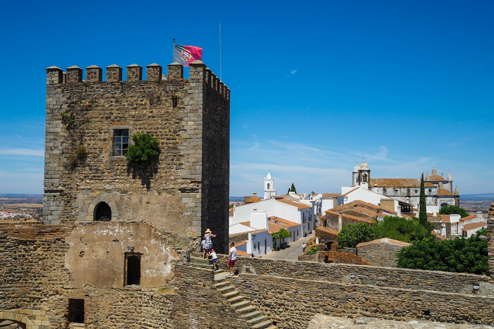 Monsaraz — a couple of people standing on top of a stone building