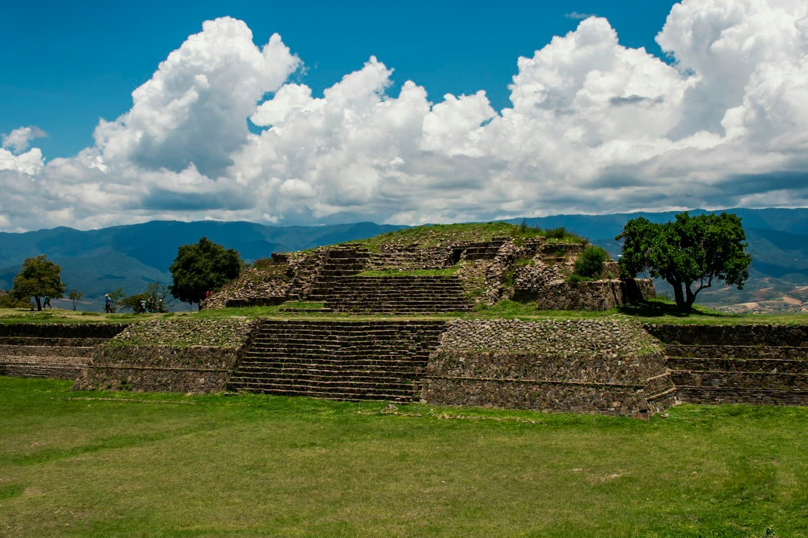 Monte Alban — brown brick wall on green grass field under blue sky and white clouds during daytime