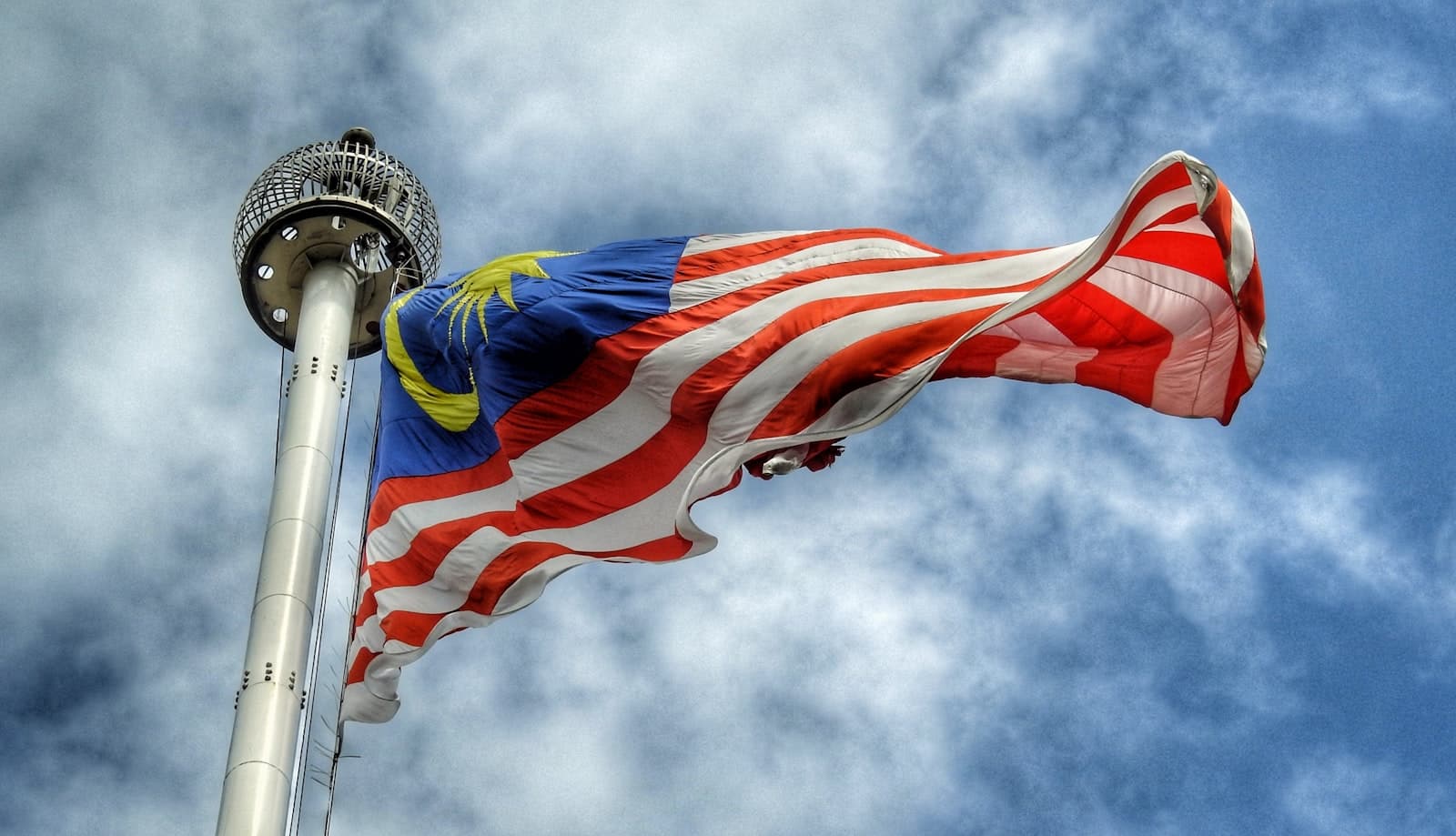 Mukah — low angle photography of waving flag of Malaysia during daytime