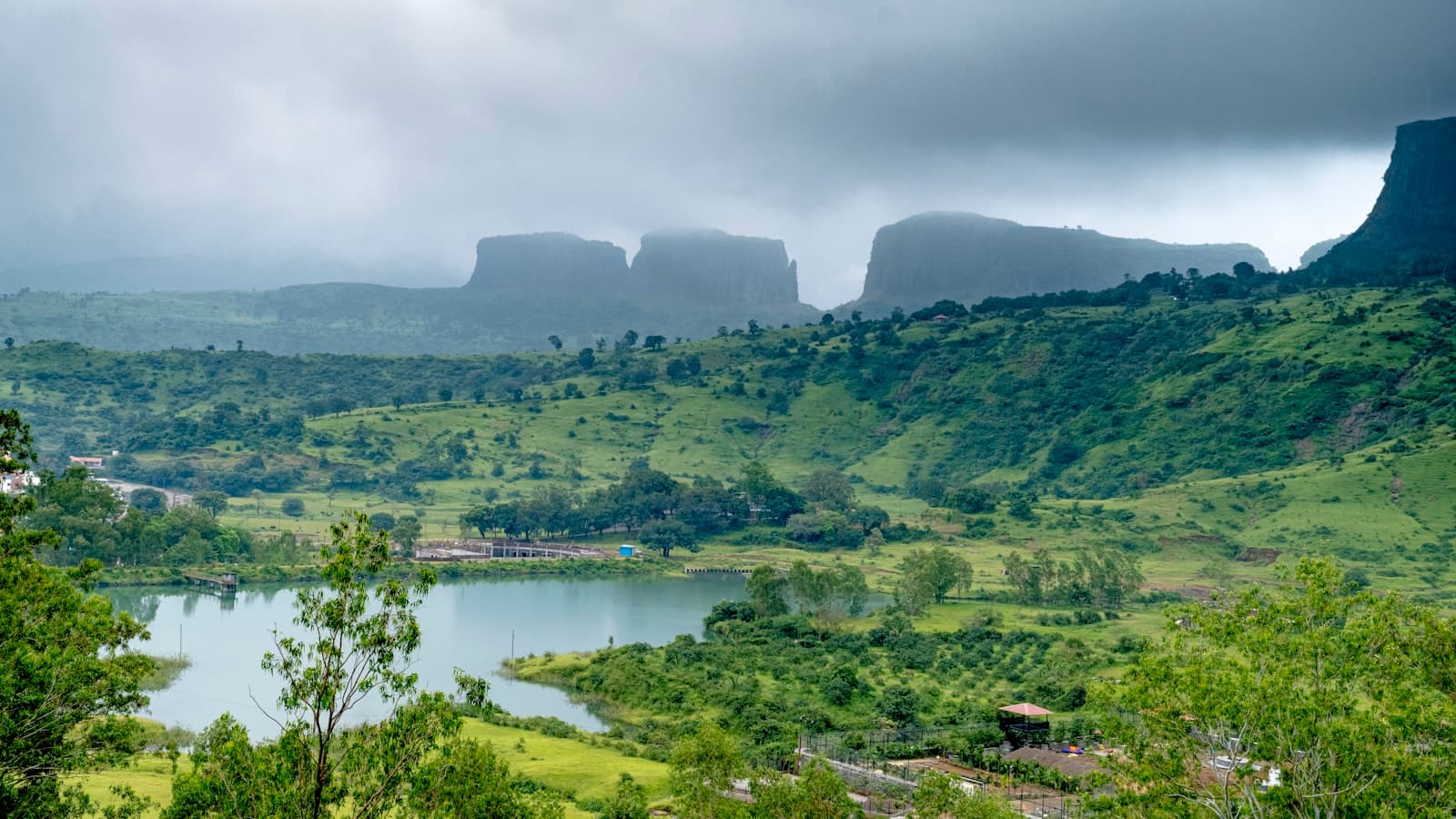 Nashik — a landscape with trees and a body of water with mountains in the background