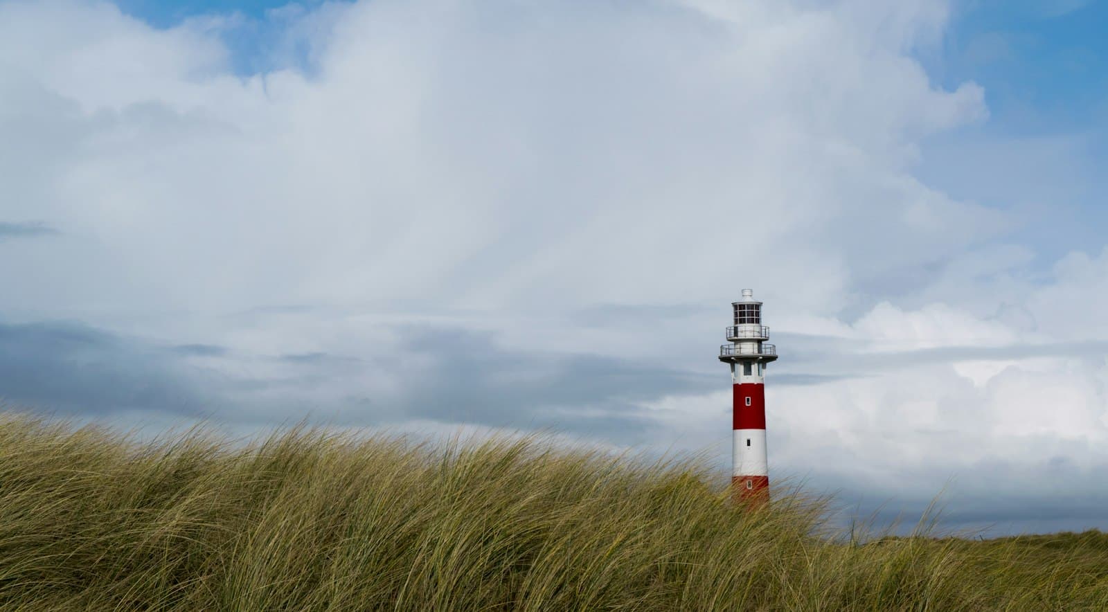 Nieuwpoort — white and red lighthouse near grassland under white clouds at daytime