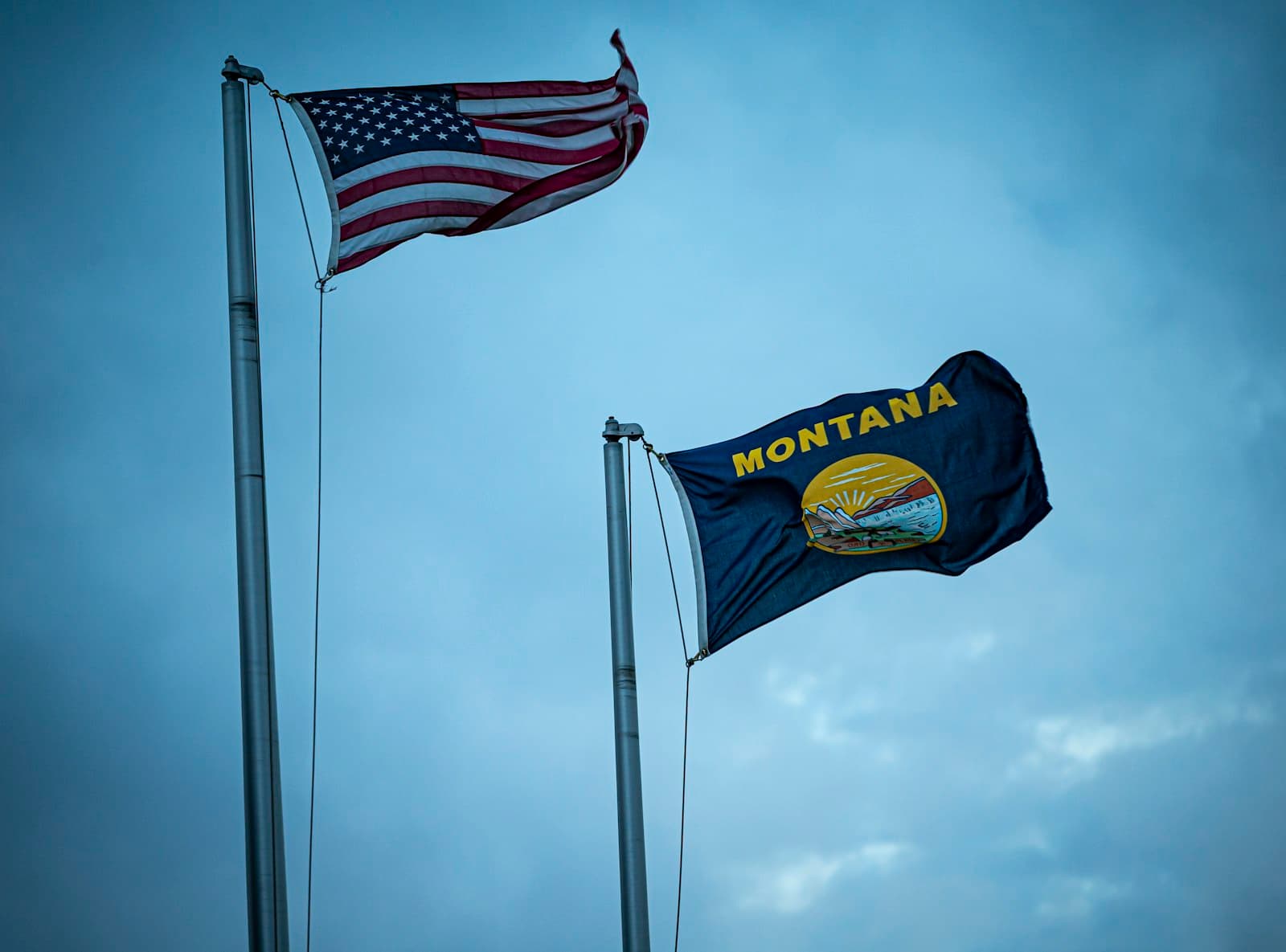Norman — American and montana flags waving against a cloudy sky
