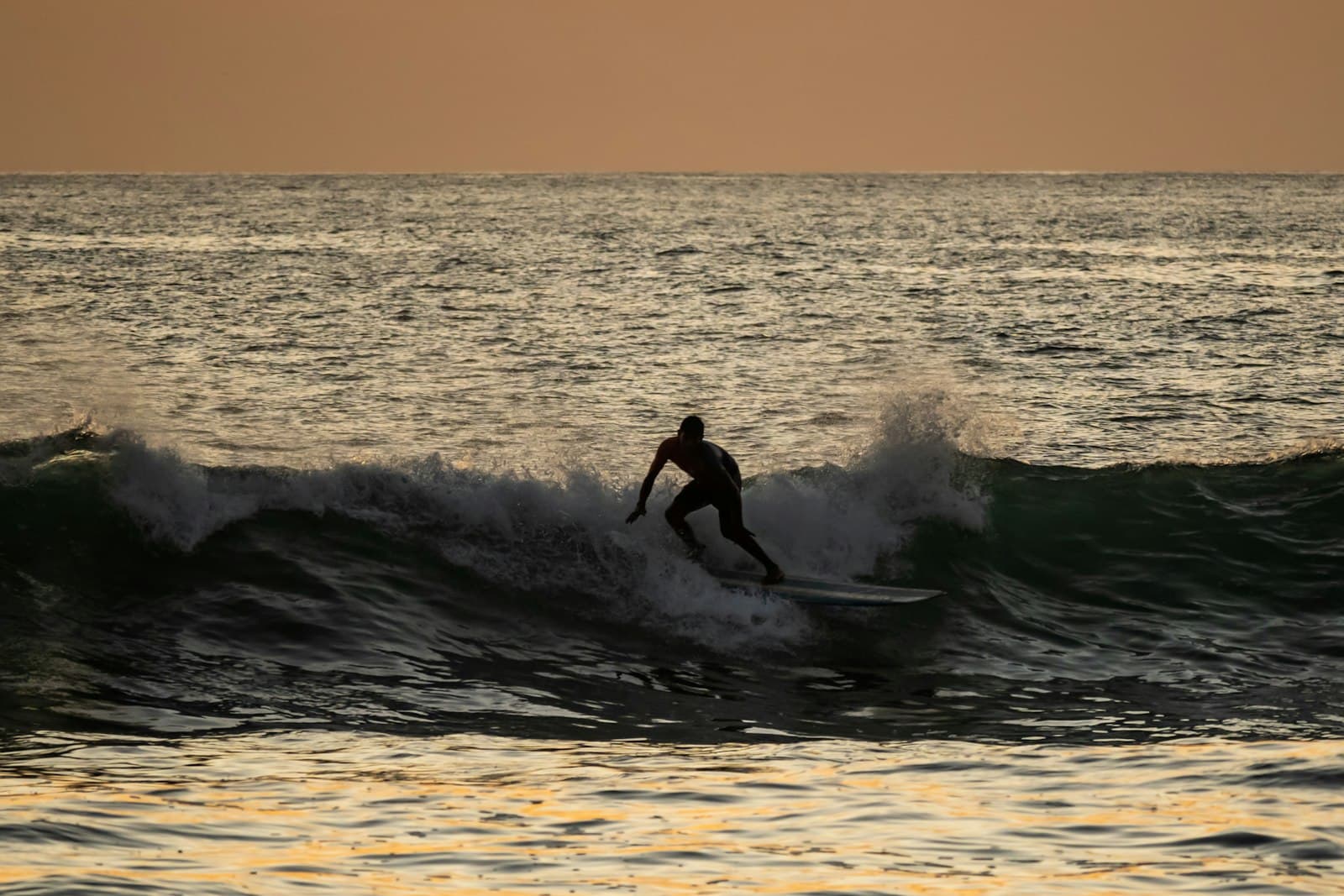Nosara — a man riding a wave on top of a surfboard
