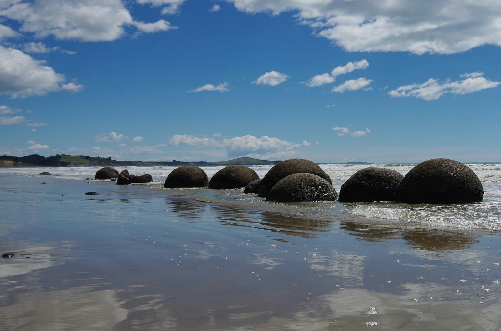 Oamaru — a group of rocks sitting on top of a sandy beach