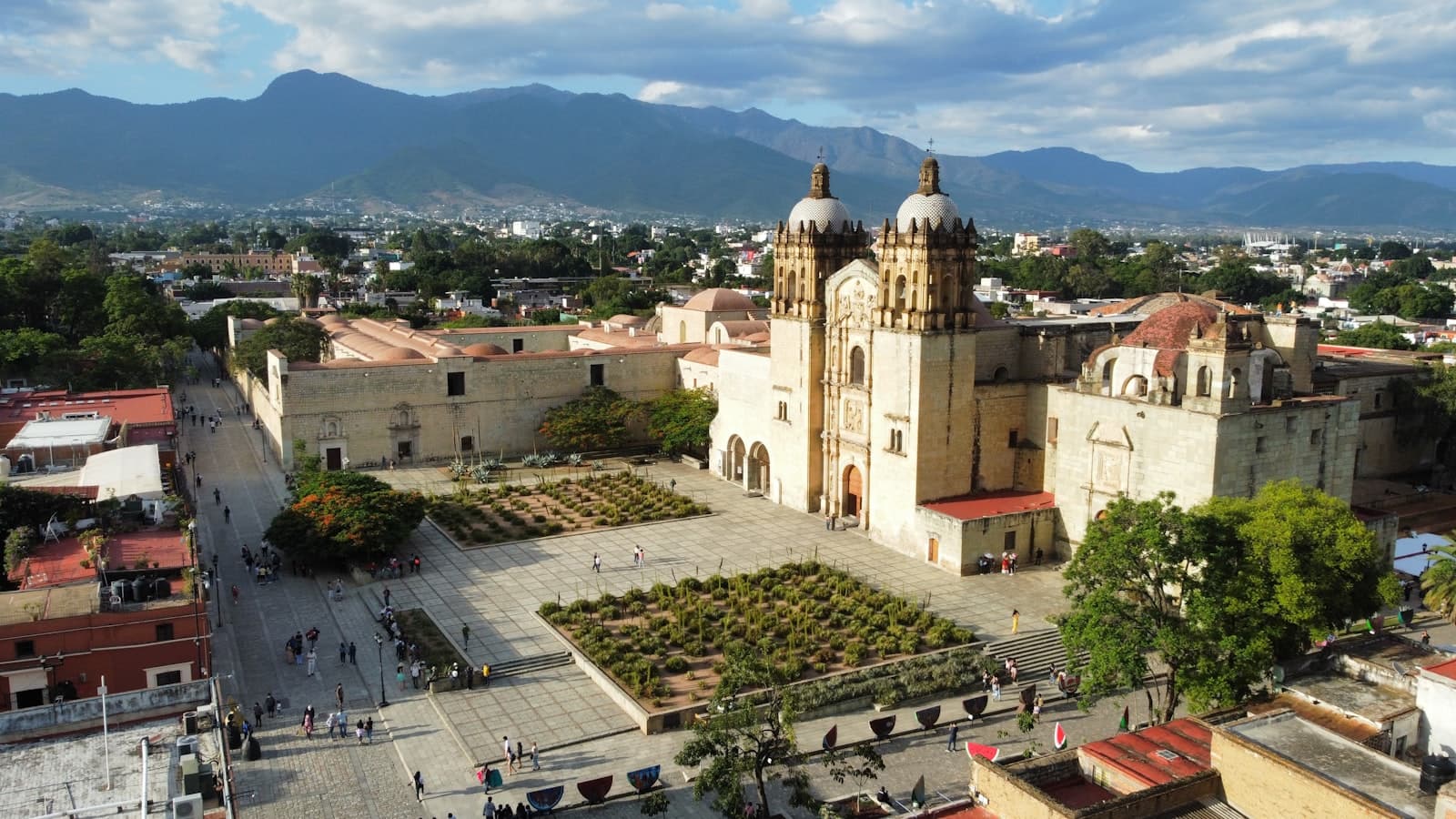 Oaxaca — a large building with a dome and a courtyard with people walking around