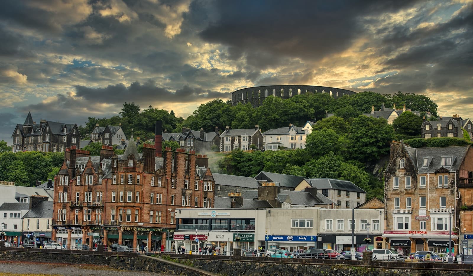 Oban — brown and white concrete buildings near green trees under white clouds and blue sky during daytime