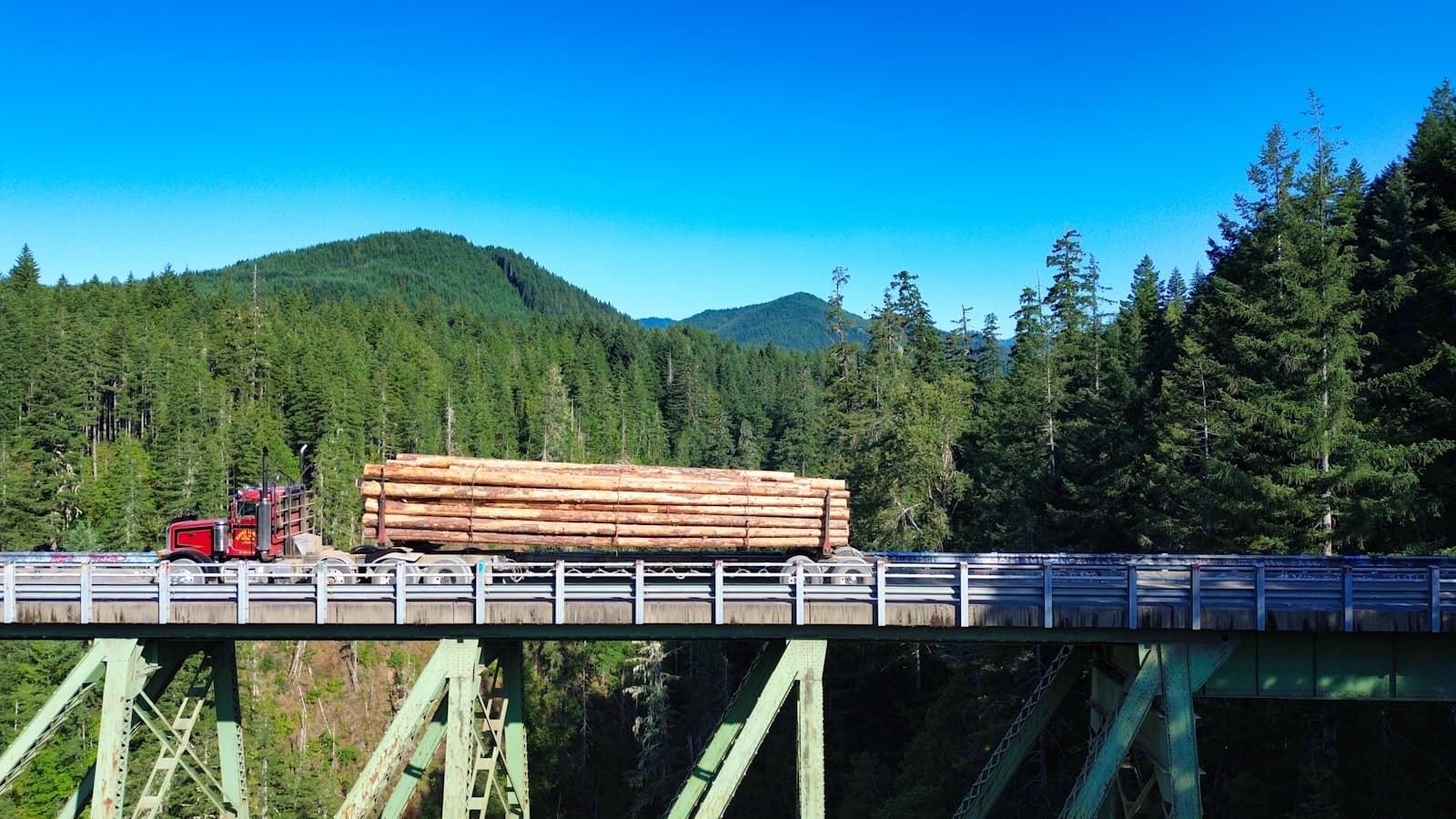 Olympia — A truck driving over a bridge with a forest in the background