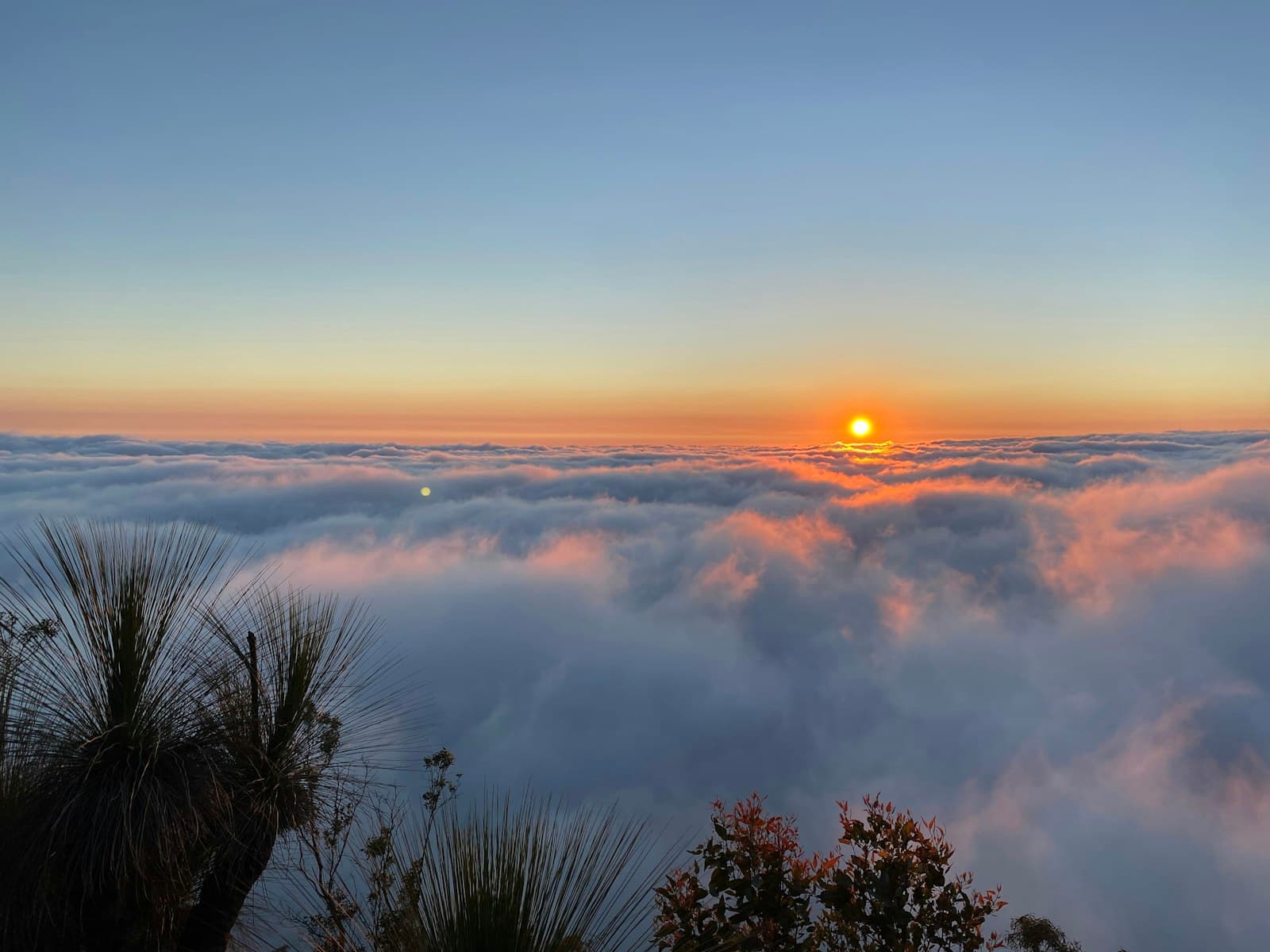 Orange — the sun is setting over the clouds in the sky