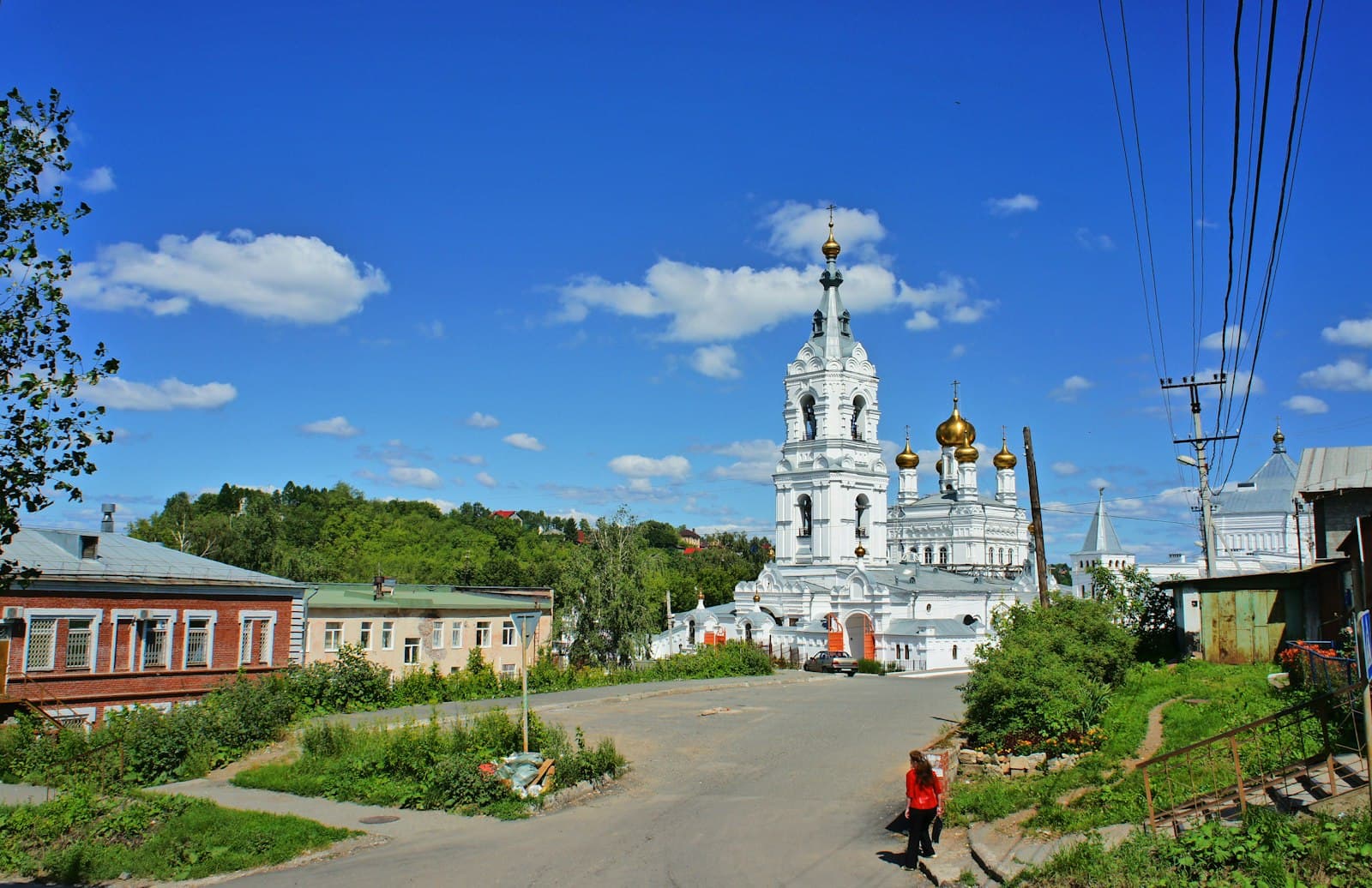 Orel — a woman walking down a street in front of a church