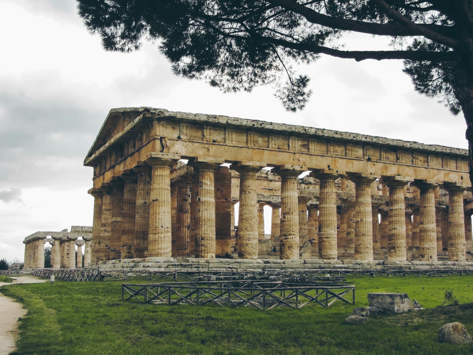 Paestum — a large stone structure sitting on top of a lush green field