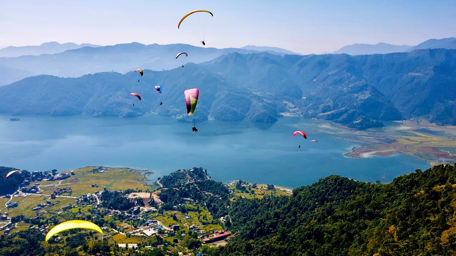 Pokhara — people on parachute over green mountains during daytime