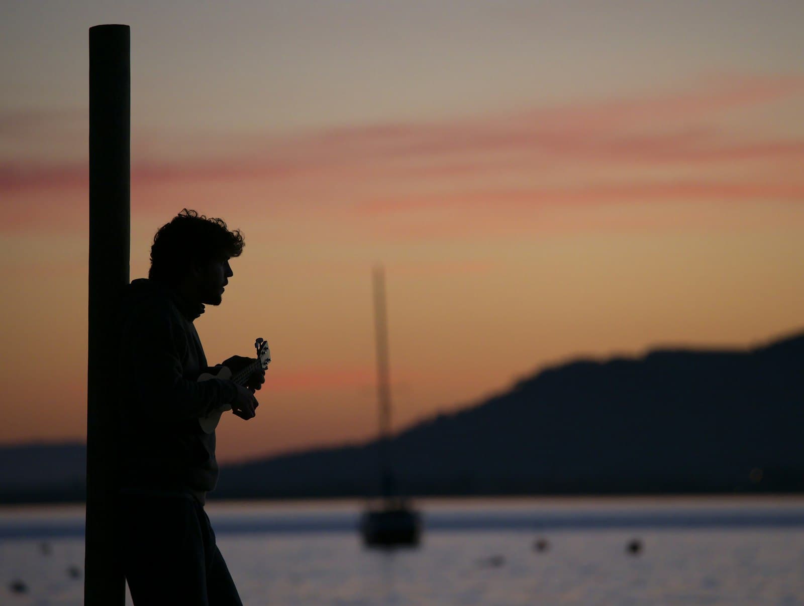 Pollença — a man standing next to a pole near a body of water