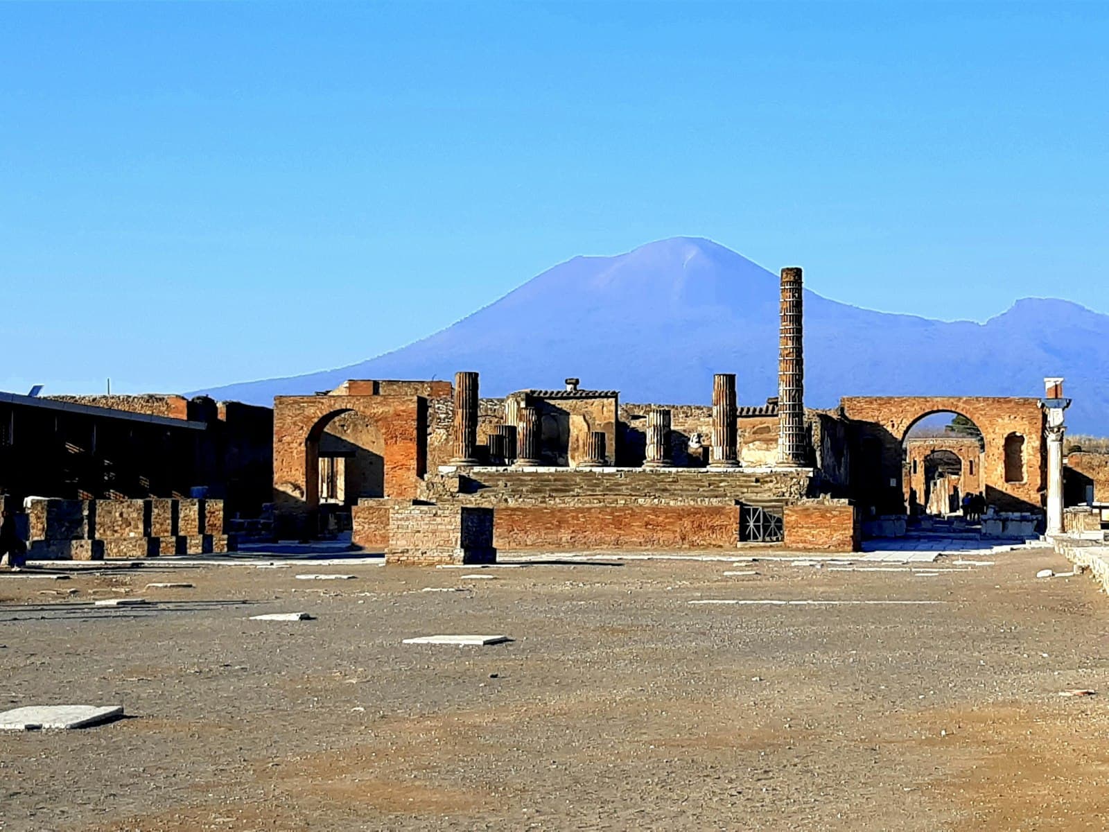 Pompeii — brown concrete building near mountain under blue sky during daytime