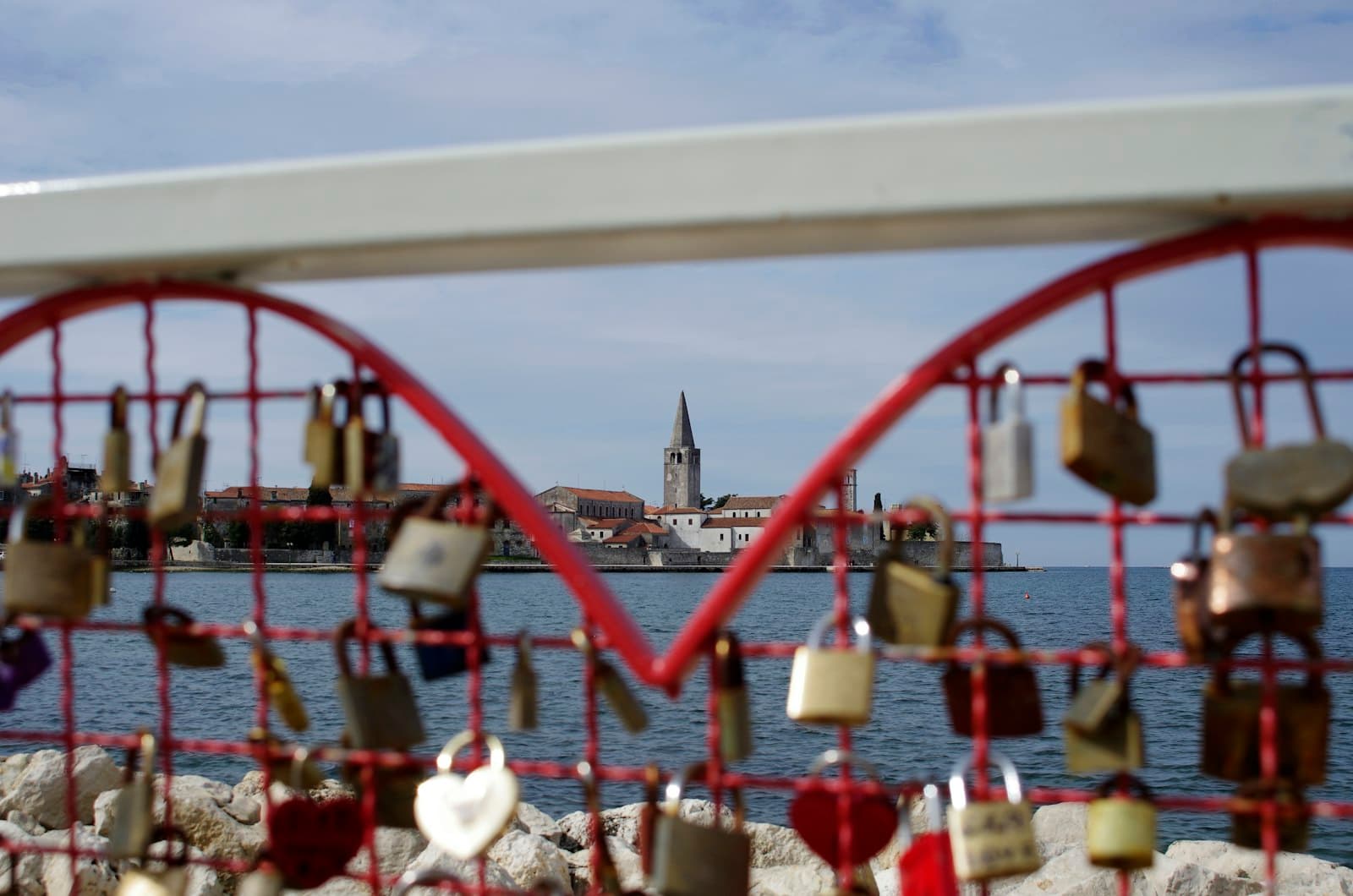 Poreč — many padlocks are attached to a fence near a body of water