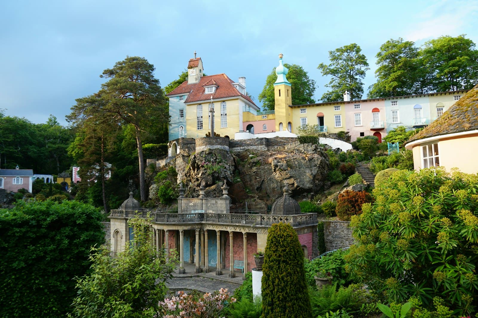 Portmeirion — A house on a hill surrounded by trees and bushes